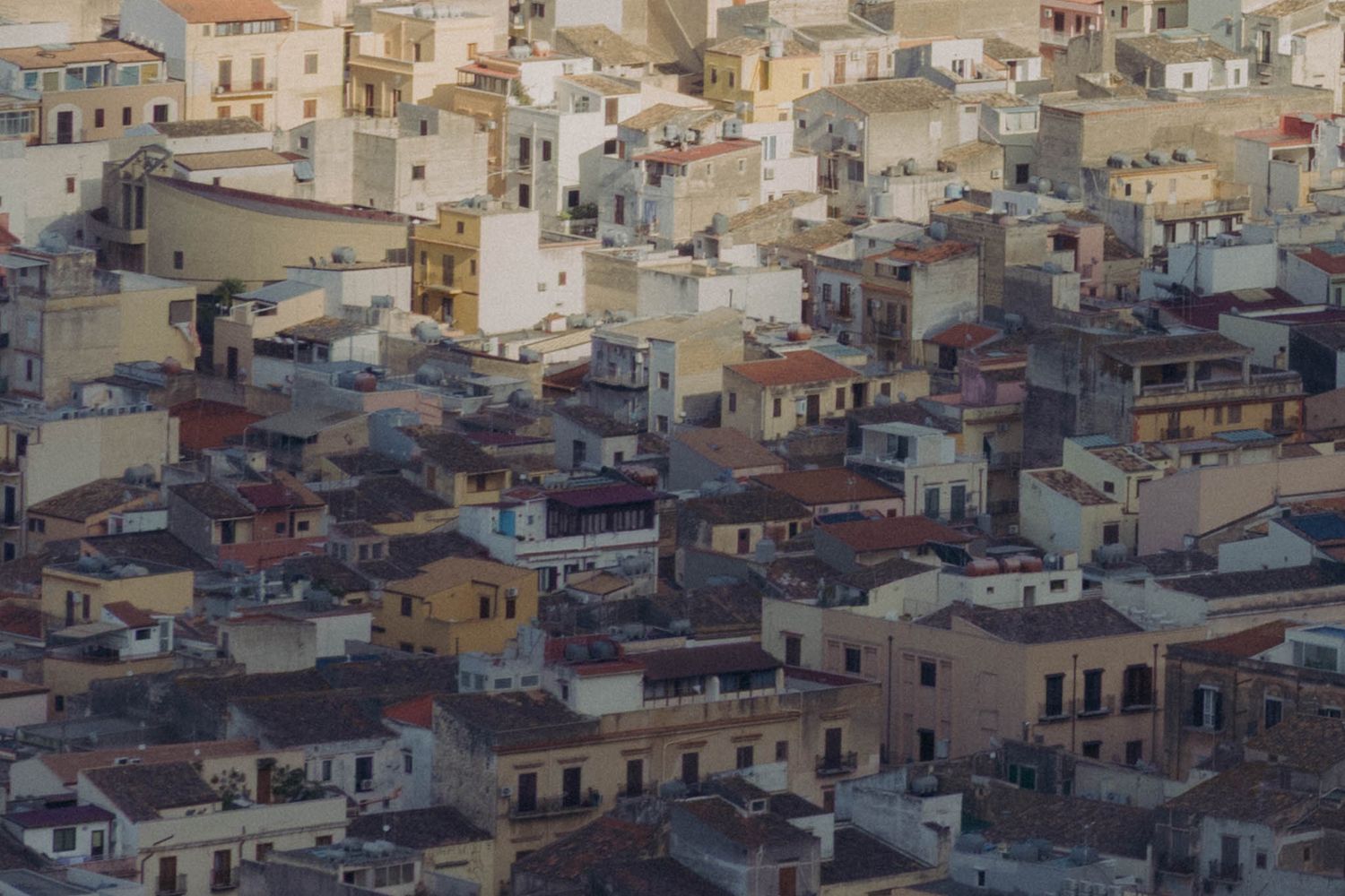 Aerial panoramic view of densely packed buildings and rooftops in an old Mediterranean city district.
