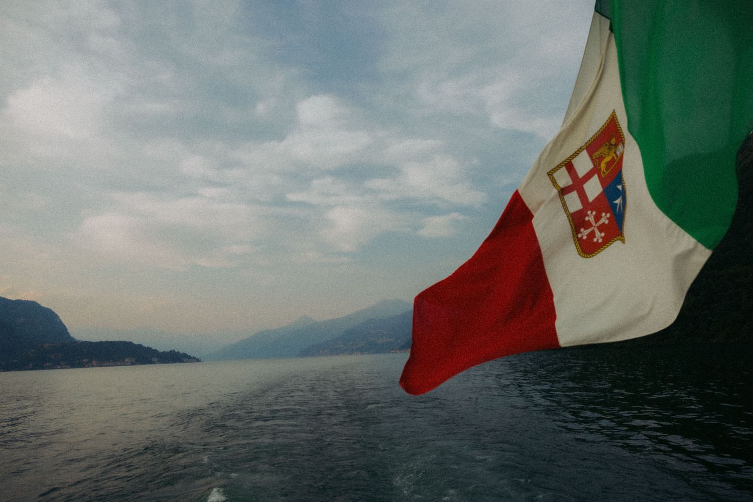 A collection of five landscape photos showing coastal views with Italian flags flying in the foreground.