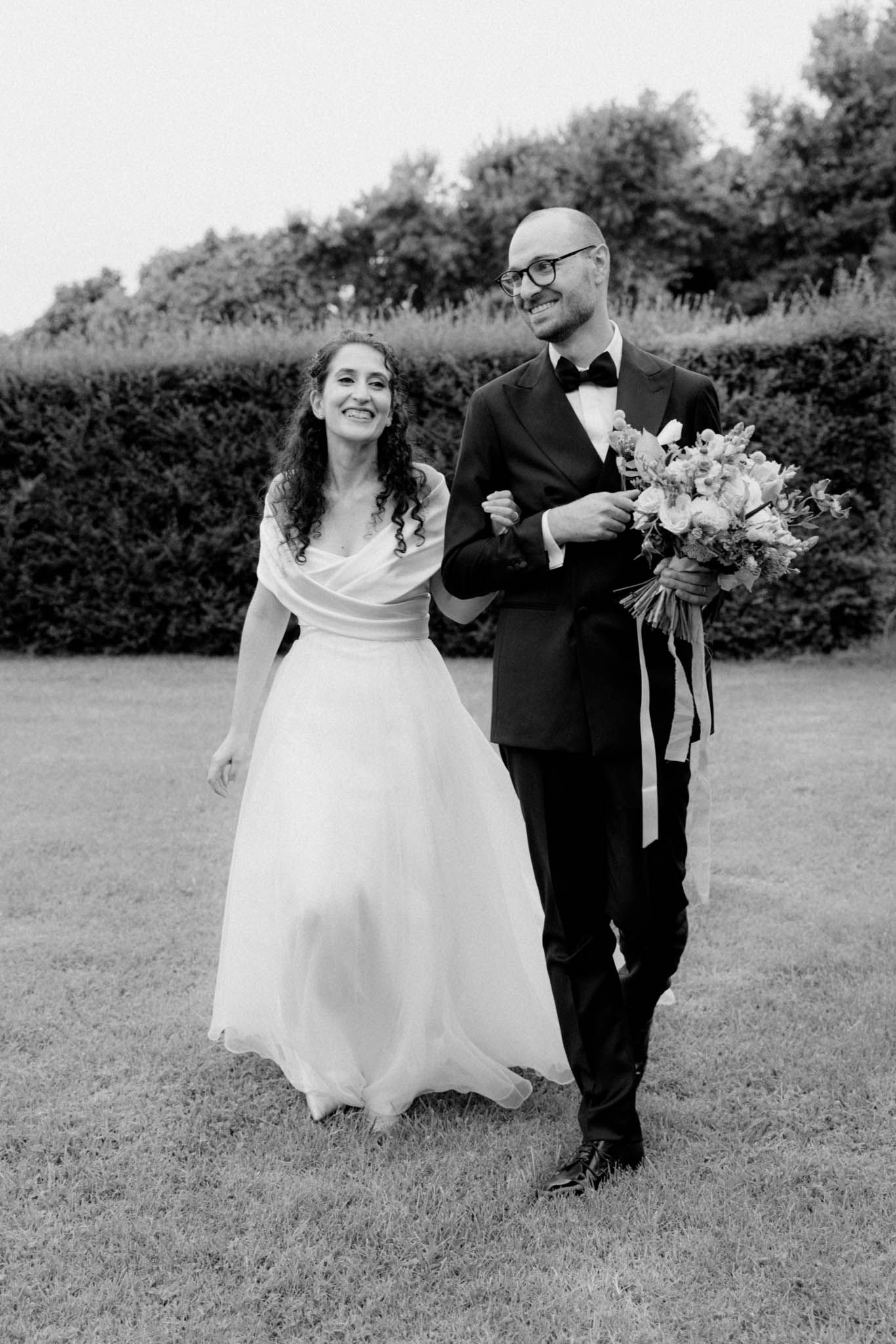 A series of black and white wedding photos showing playful moments between a bride and groom outdoors.