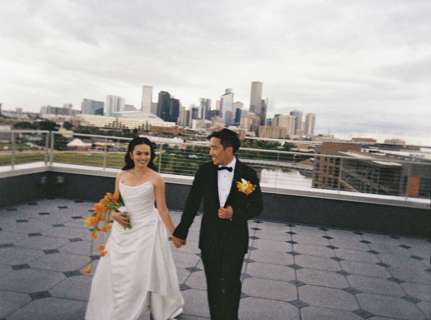A wedding party poses on a rooftop terrace with the Minneapolis city skyline visible in the background.