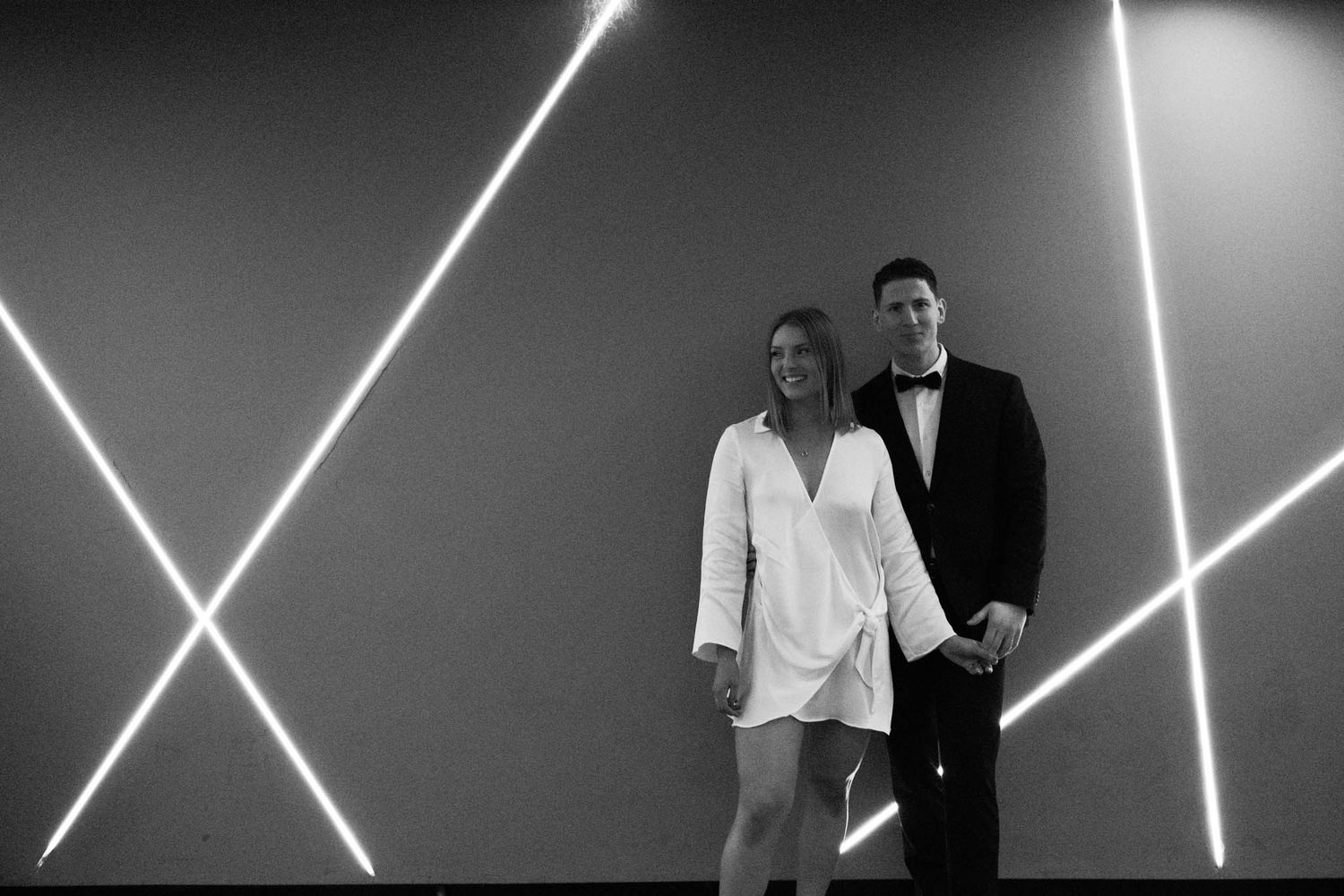 Black and white photograph showing people posing against a wall with dramatic angular lighting patterns.