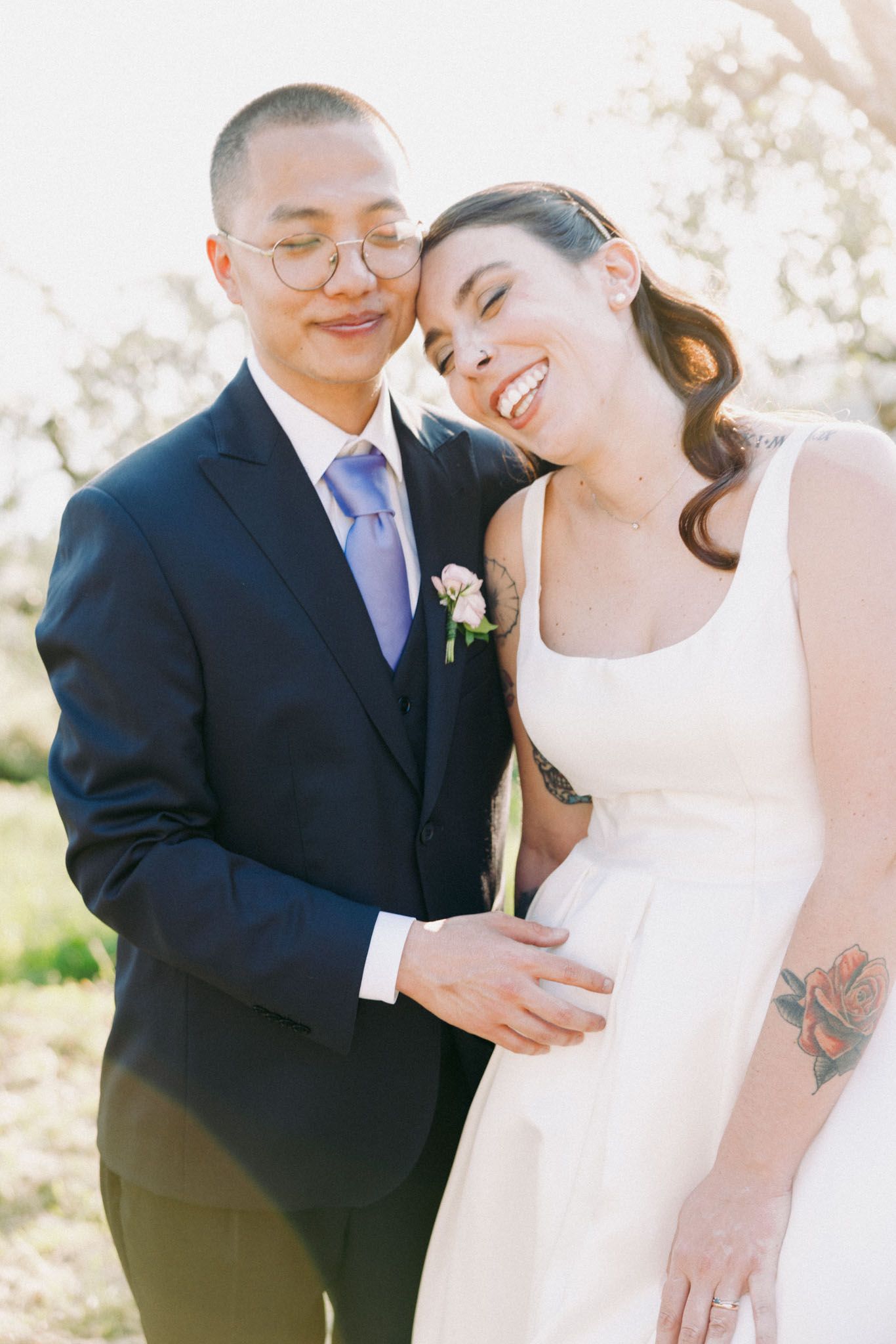 Couple shares intimate moments during their outdoor wedding photoshoot in warm sunlight.