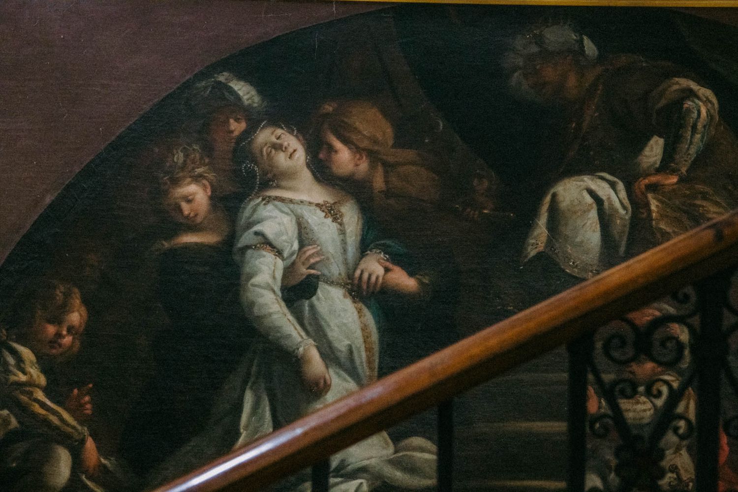 A dark classical painting depicts figures struggling with a large wooden cross in a dramatic religious scene.