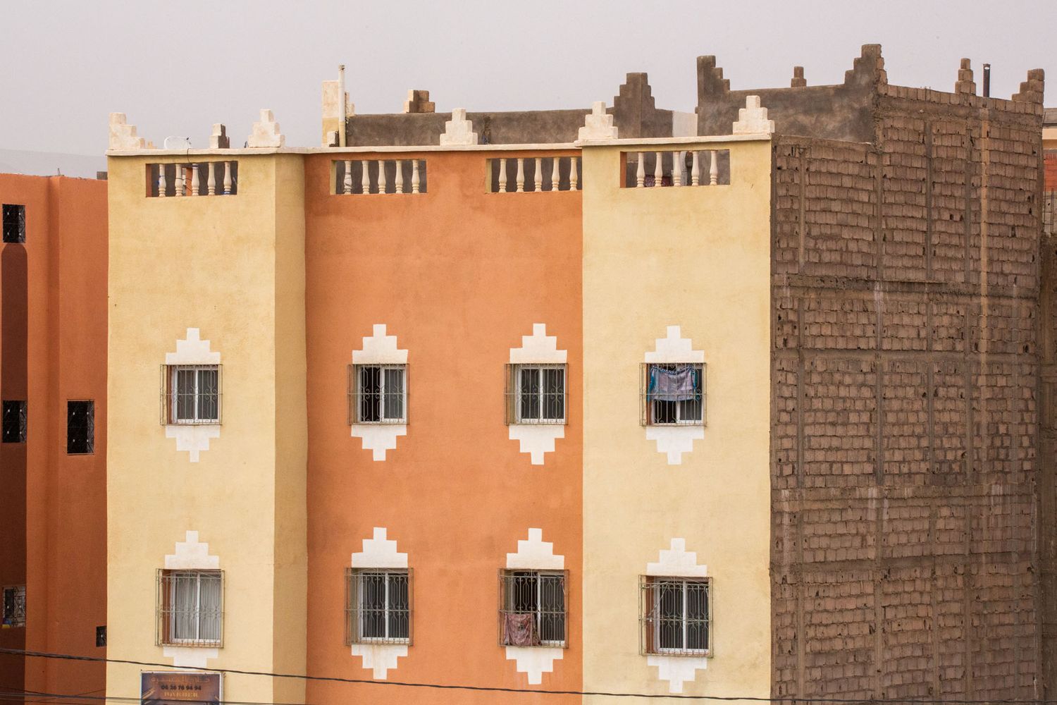 Row of uniform windows with white decorative elements on a terracotta-colored building exterior.