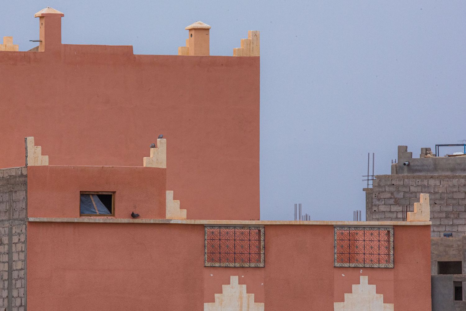Desert landscape with orange-tinted buildings and blue sky in an arid urban setting.