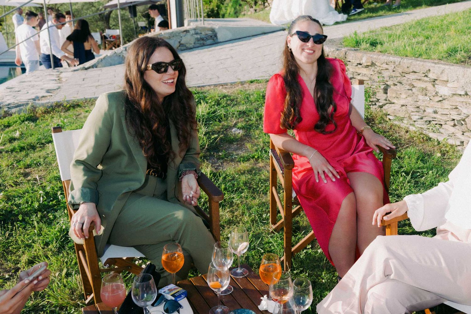 A group enjoying a picnic outdoors with wine glasses and snacks on a sunny afternoon.