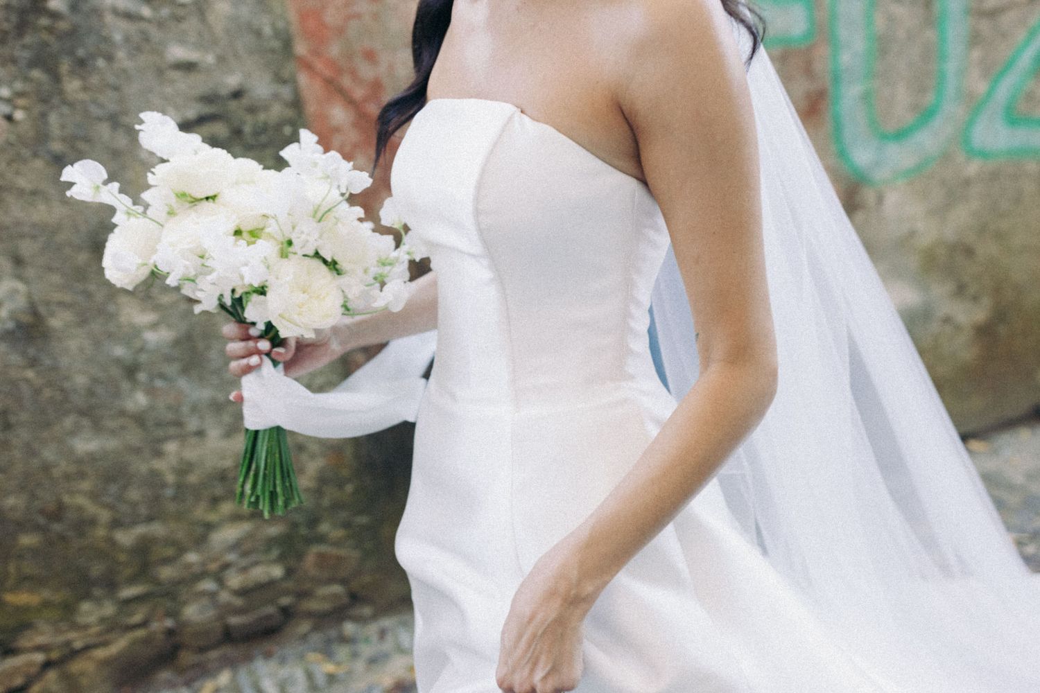 A series of wedding photos showing a bride in a white gown holding a bouquet of white flowers against a stone wall.