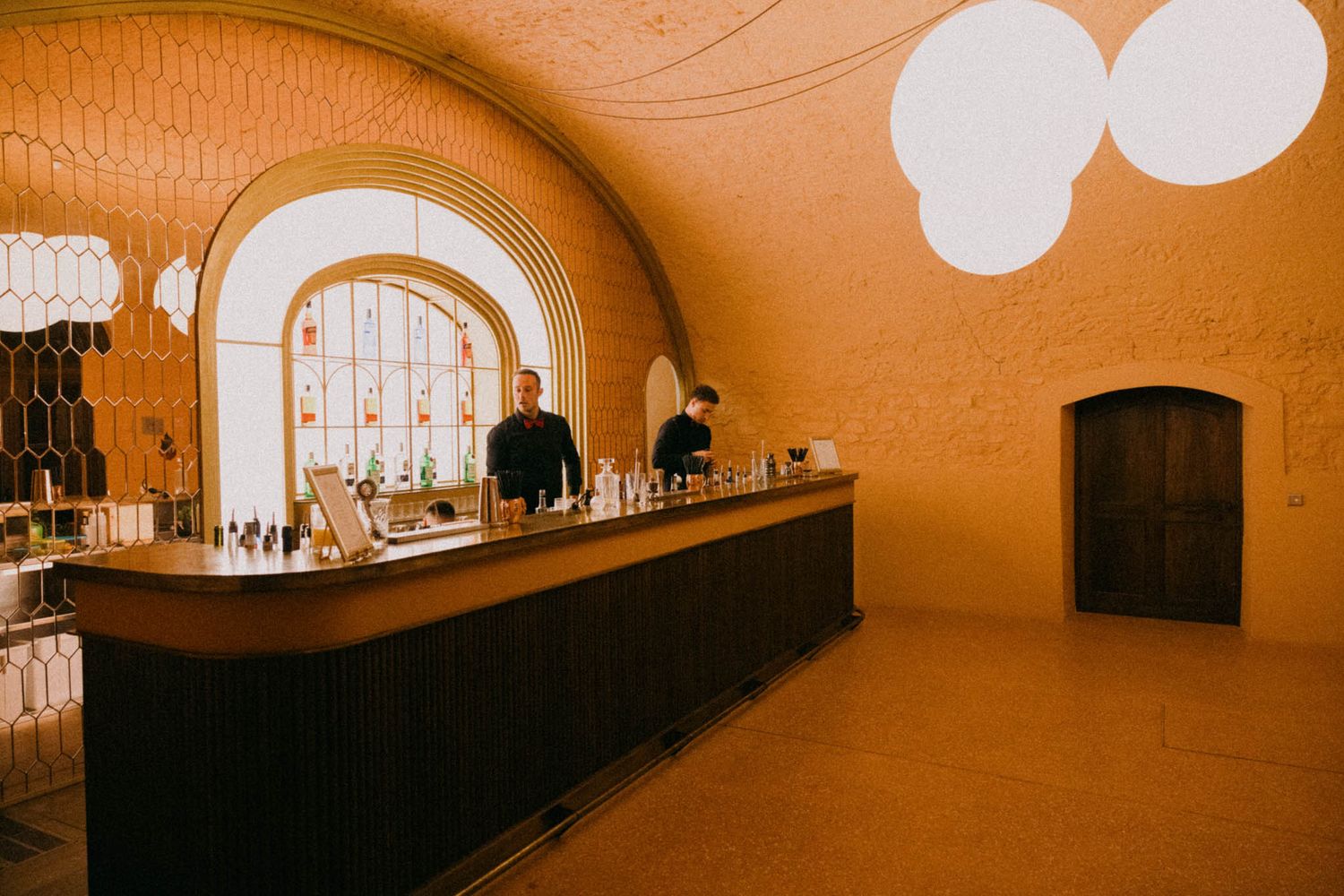 Warm-toned interior view of an arched wine cellar with curved walls and ambient lighting creating a cozy atmosphere.