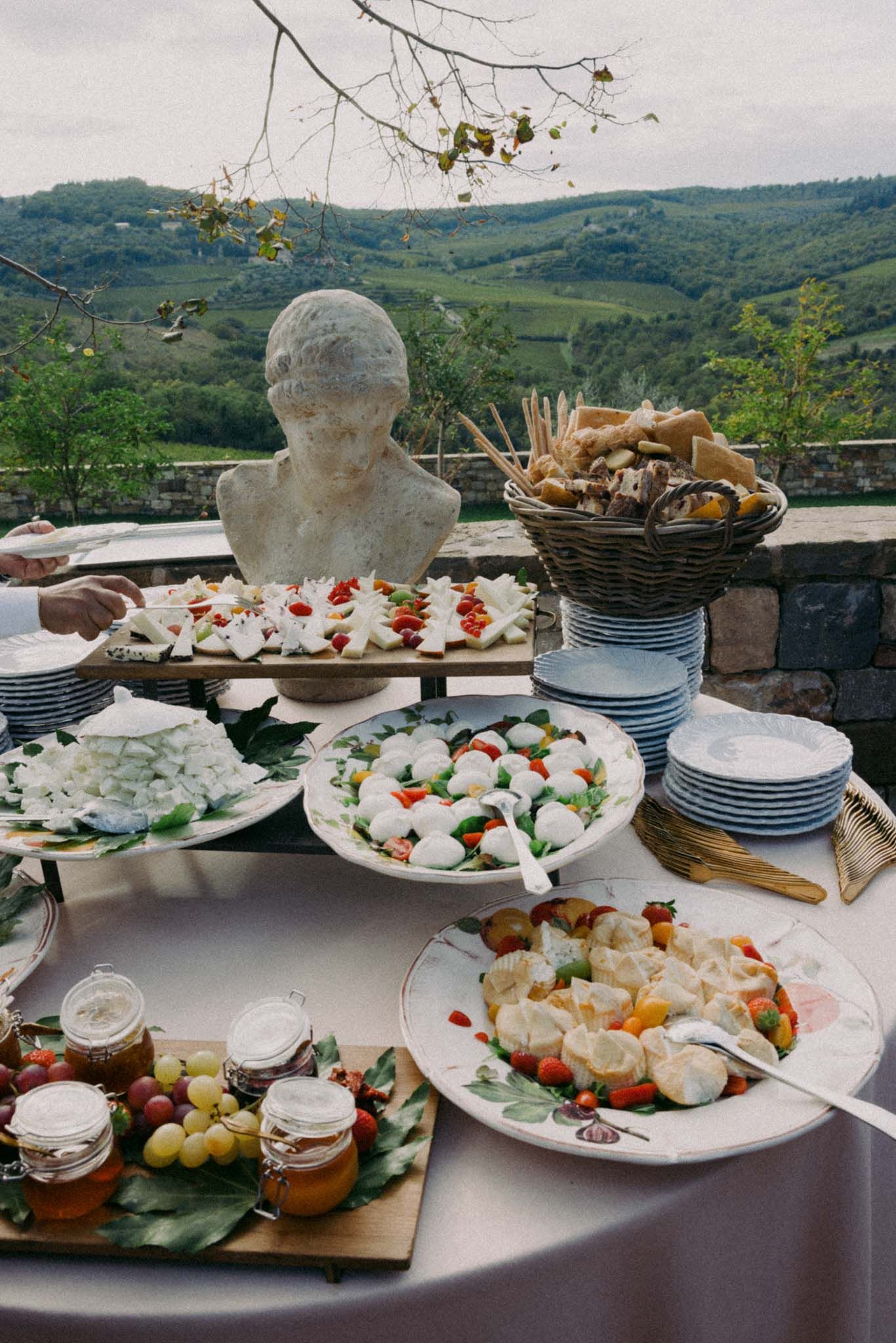 Elegant catering display of appetizers and dishes on white plates overlooking a scenic mountain landscape view.