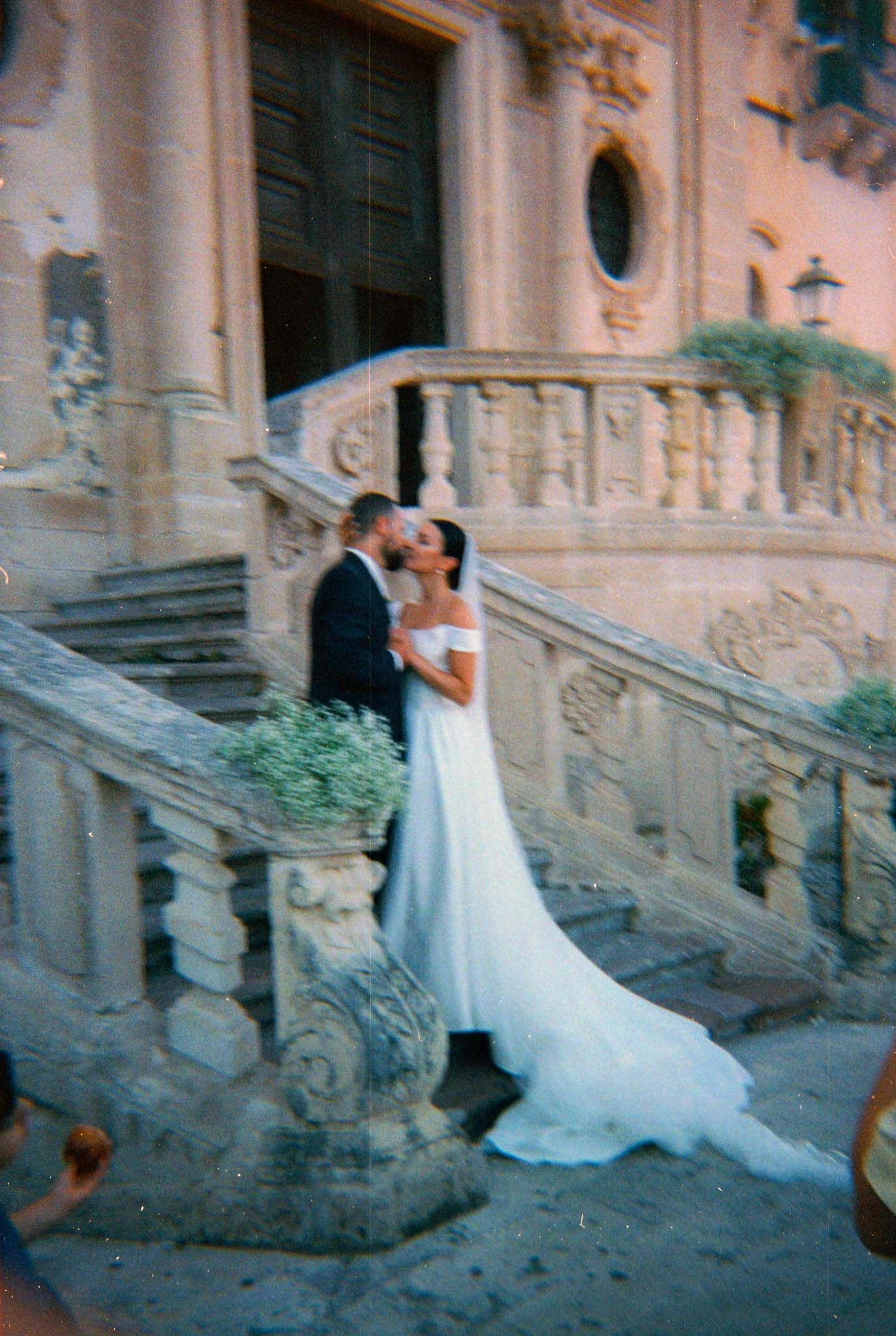 A couple in wedding attire poses on ornate stone steps of a historic building in a romantic sequence of photos.