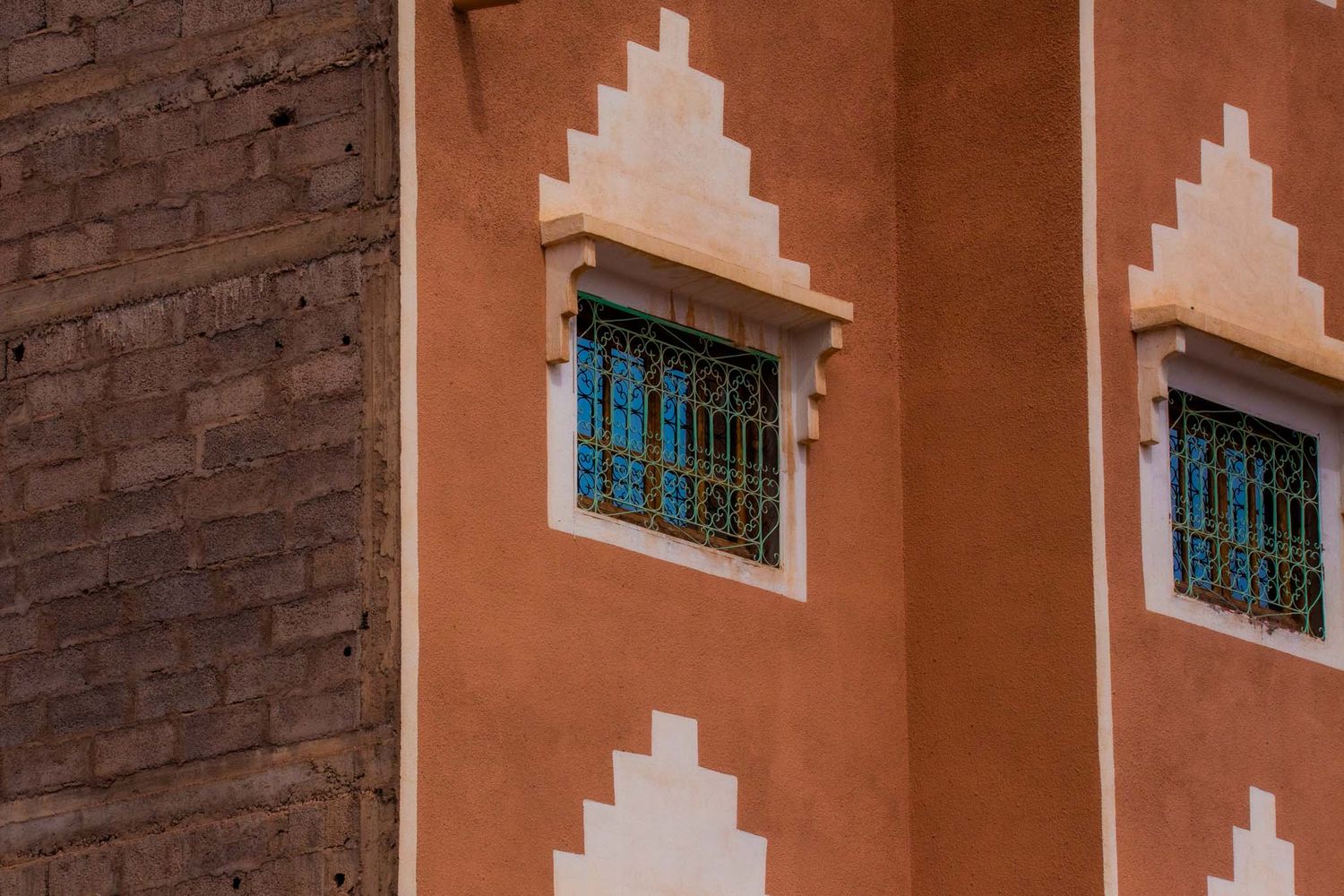 Architectural detail of a brick and terracotta building facade with stepped geometric patterns and small windows.