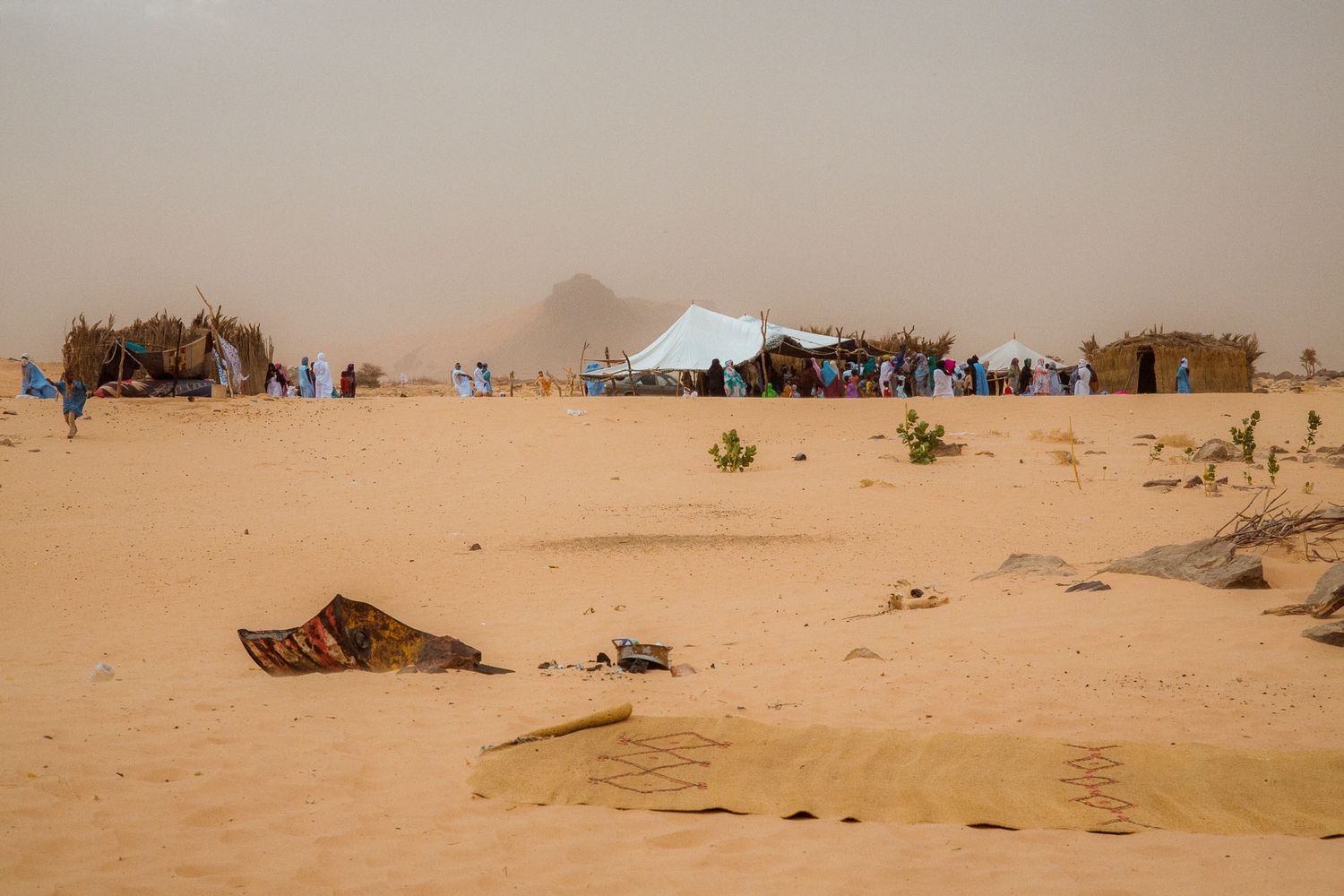 Vast desert landscape with rolling sand dunes stretching to the horizon under a warm beige sky.