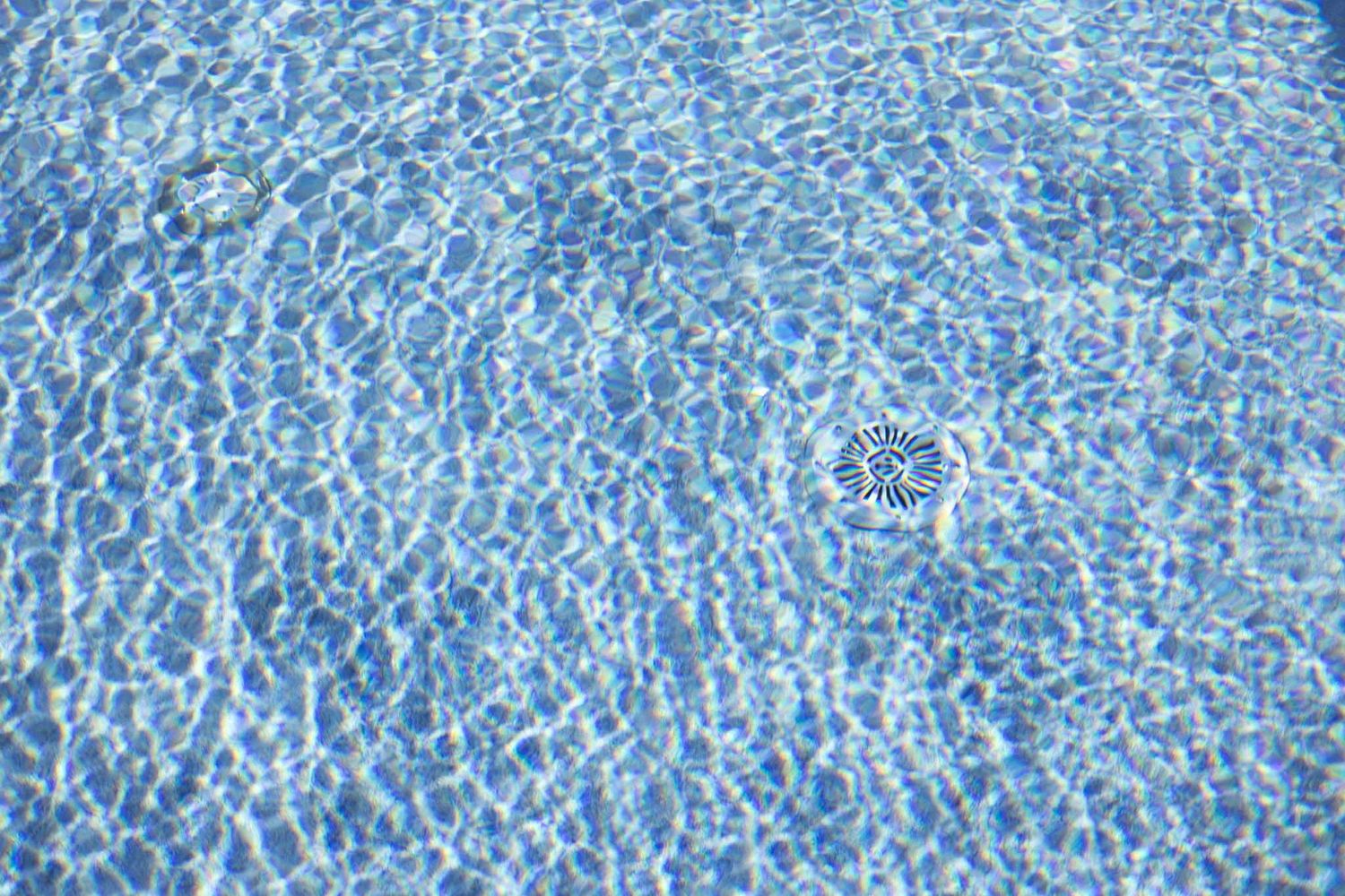 Rippling blue swimming pool water creates mesmerizing patterns and reflections in bright sunlight.