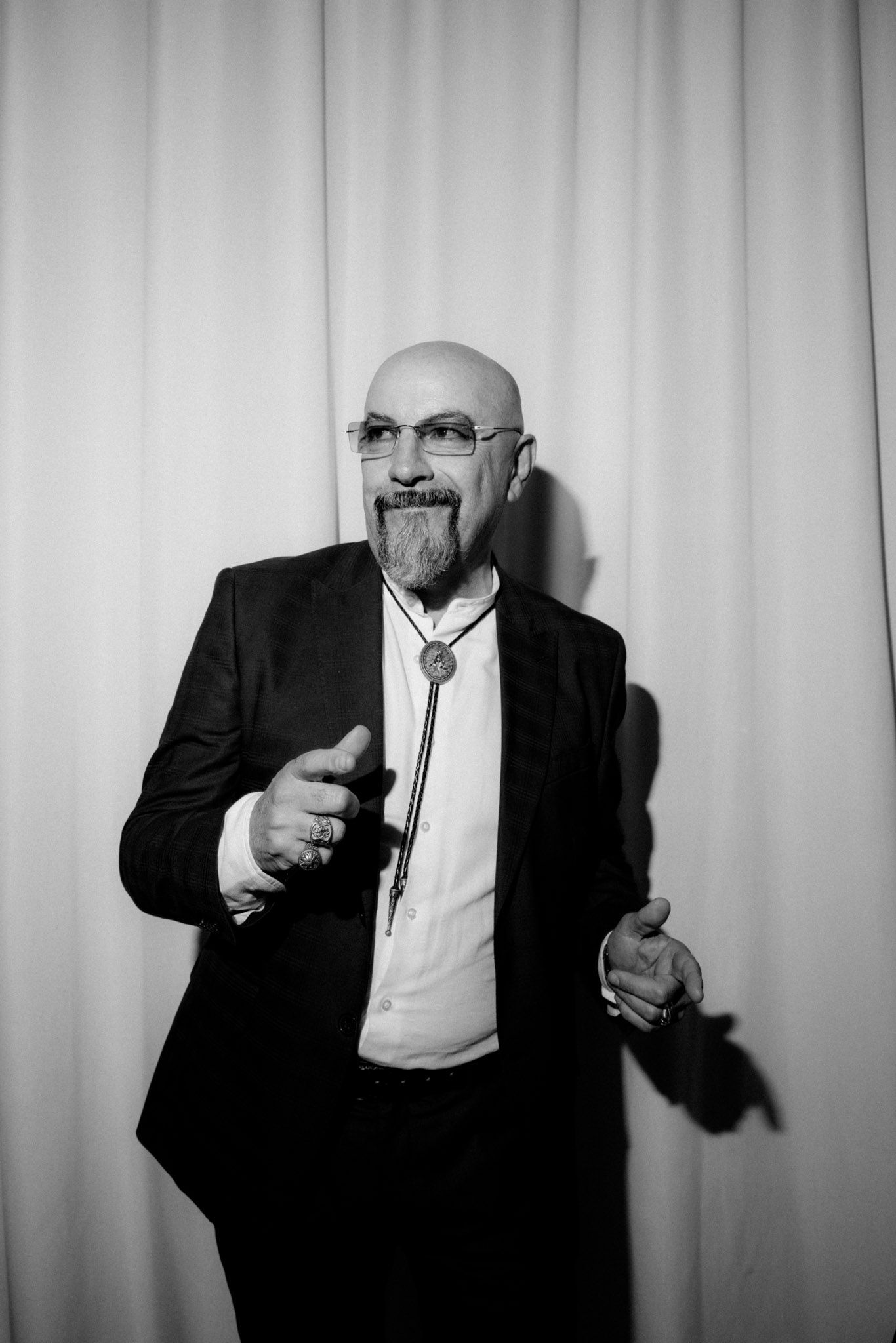 Black and white photo series showing a man in suit gesturing with a glass in dramatic poses against white backdrop.