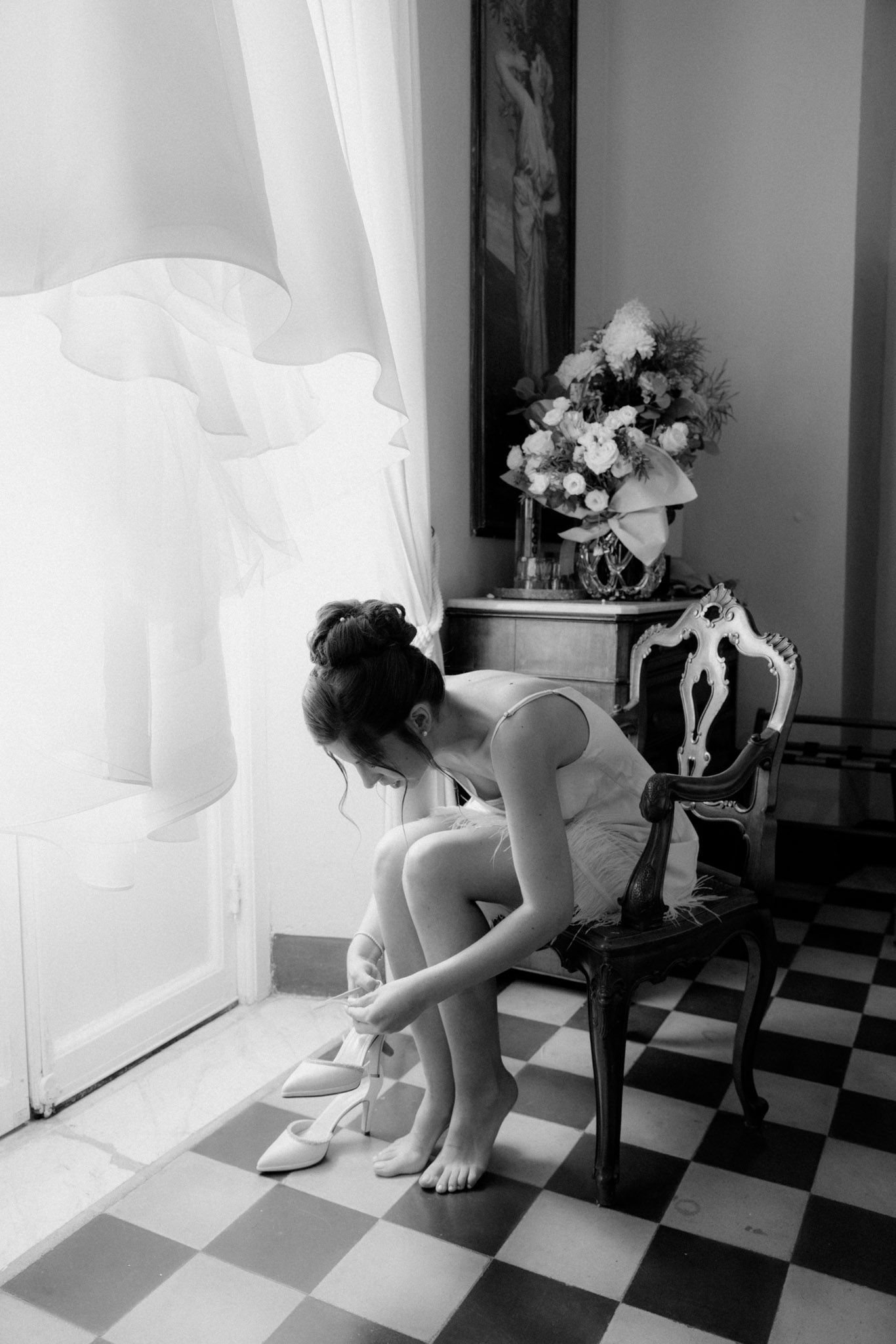 A series of black and white photographs showing a figure in white near a window on a checkered floor with floral decor.