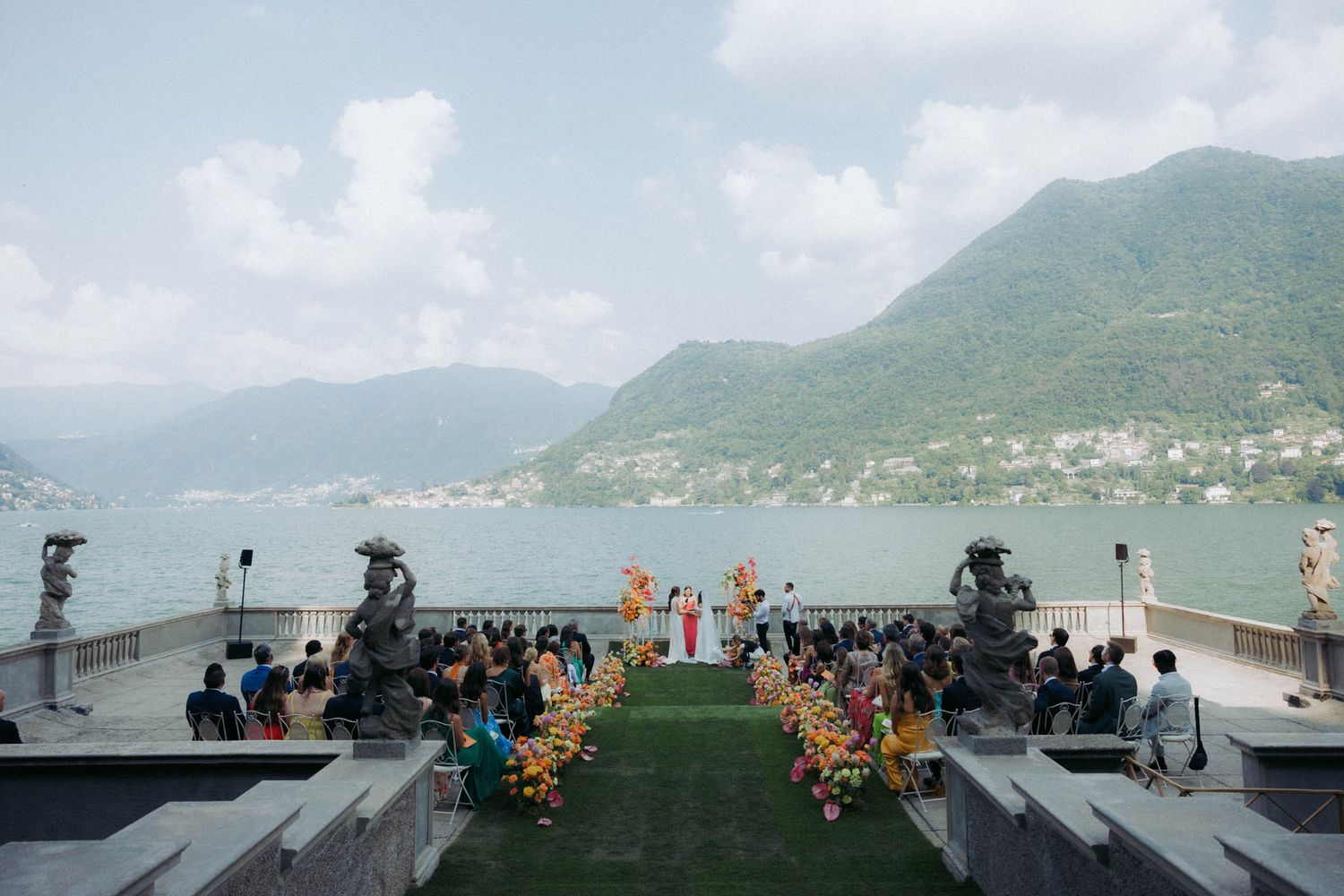 Panoramic view of a coastal mountain landscape with a crowd gathered on a misty observation deck.