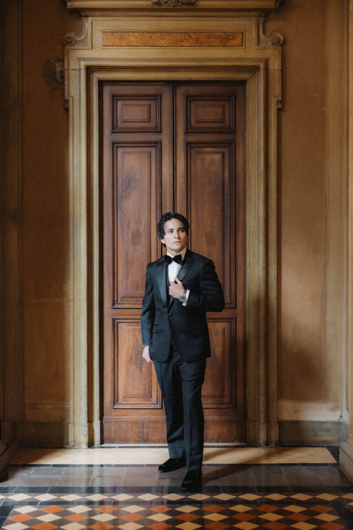 A sequence of four photos shows a person in a black suit standing in different poses against wooden doors in an elegant hallway.