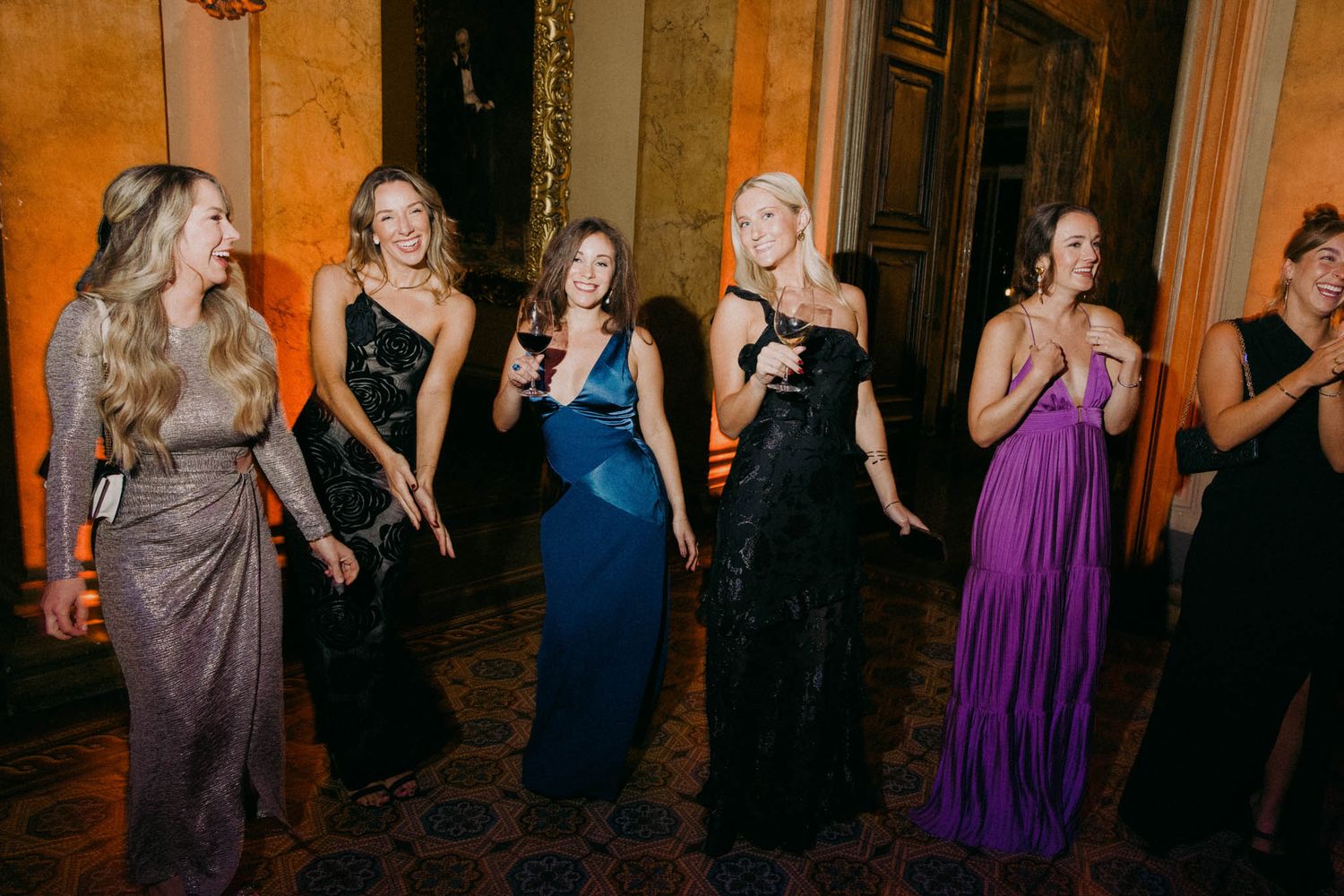 Wedding guests dancing and celebrating at an evening reception in a luxurious ballroom setting.
