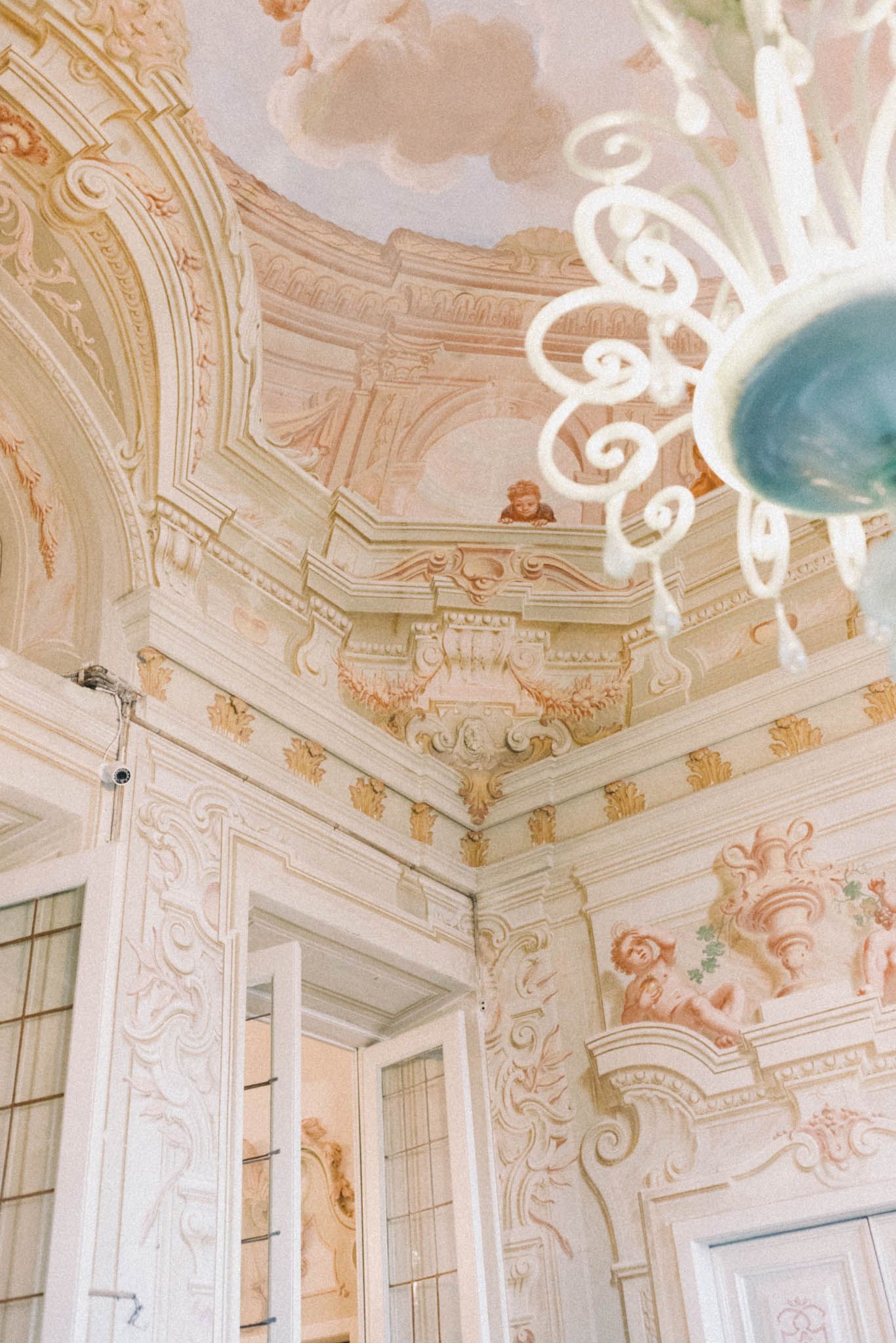 Ornate baroque ceiling with delicate pink and gold decorative plasterwork and crystal chandeliers.