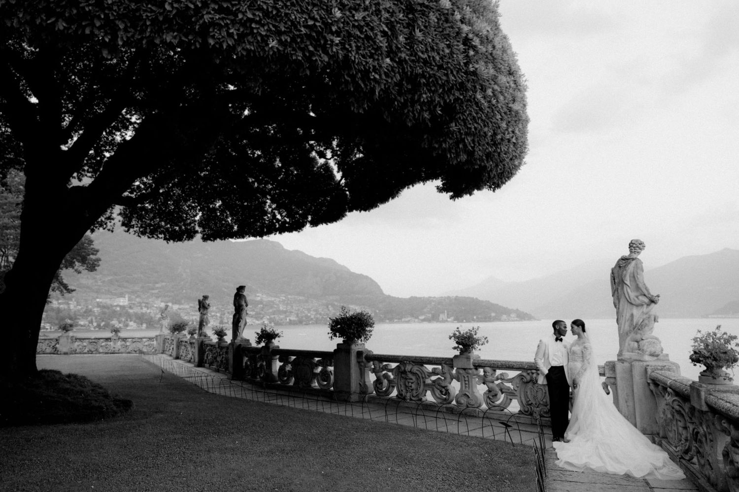 Black and white landscape photo of a tree-lined path with scenic mountain views.