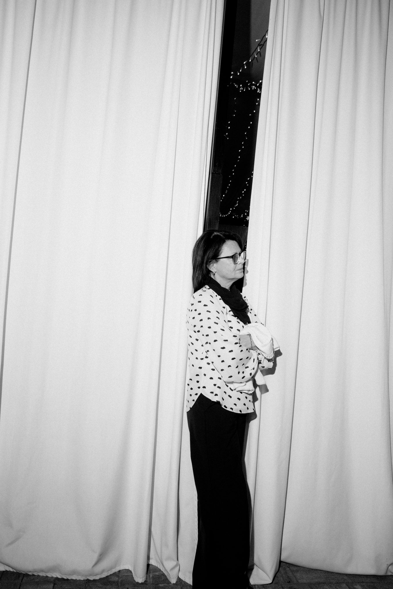 Black and white photo sequence showing someone peeking out from behind white curtains in four progressive shots.
