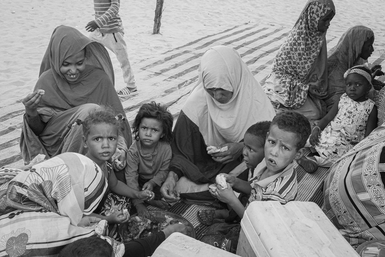 Large group of people gathered outdoors in desert environment.