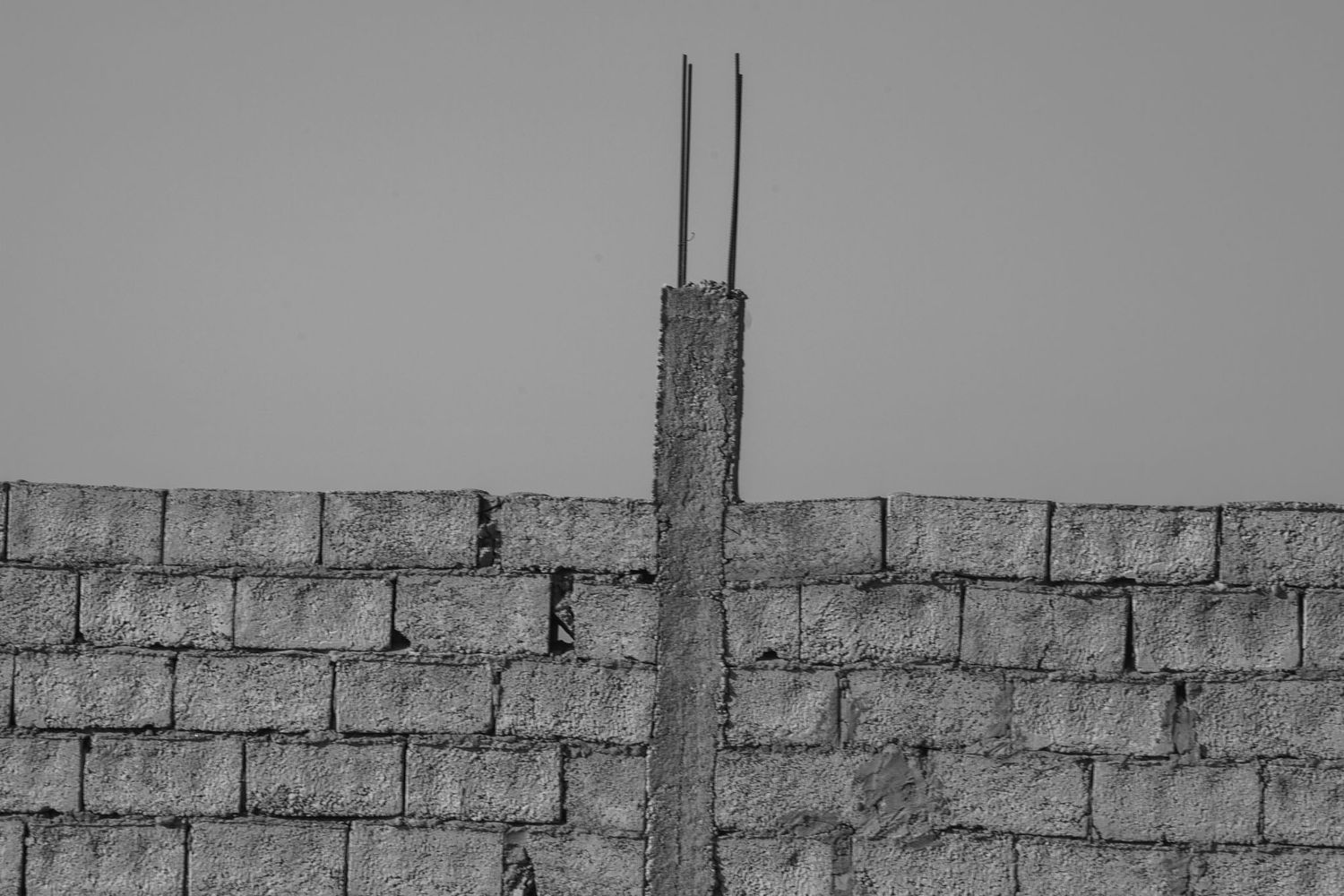 Gray brick wall with rough textured surface and horizontal pattern of stacked masonry blocks.