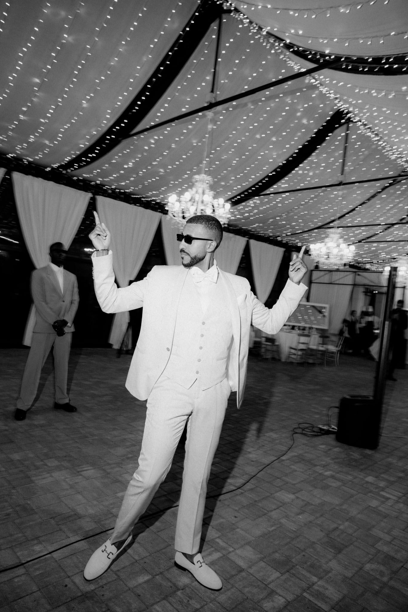 Black and white photos show people dancing at an event under a ceiling decorated with string lights and fabric draping.