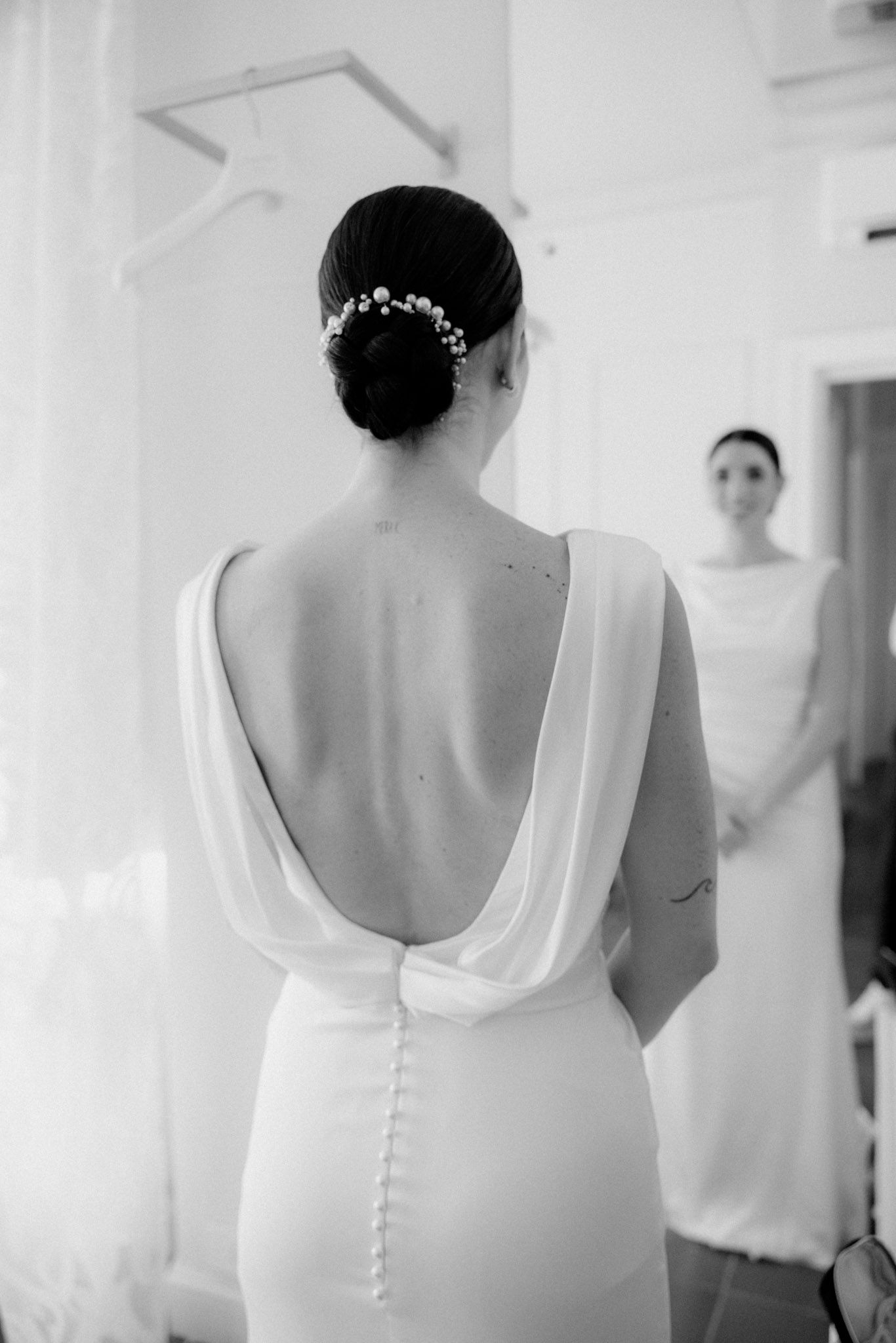 Close-up view of a white wedding dress back with delicate button details and low cut design.