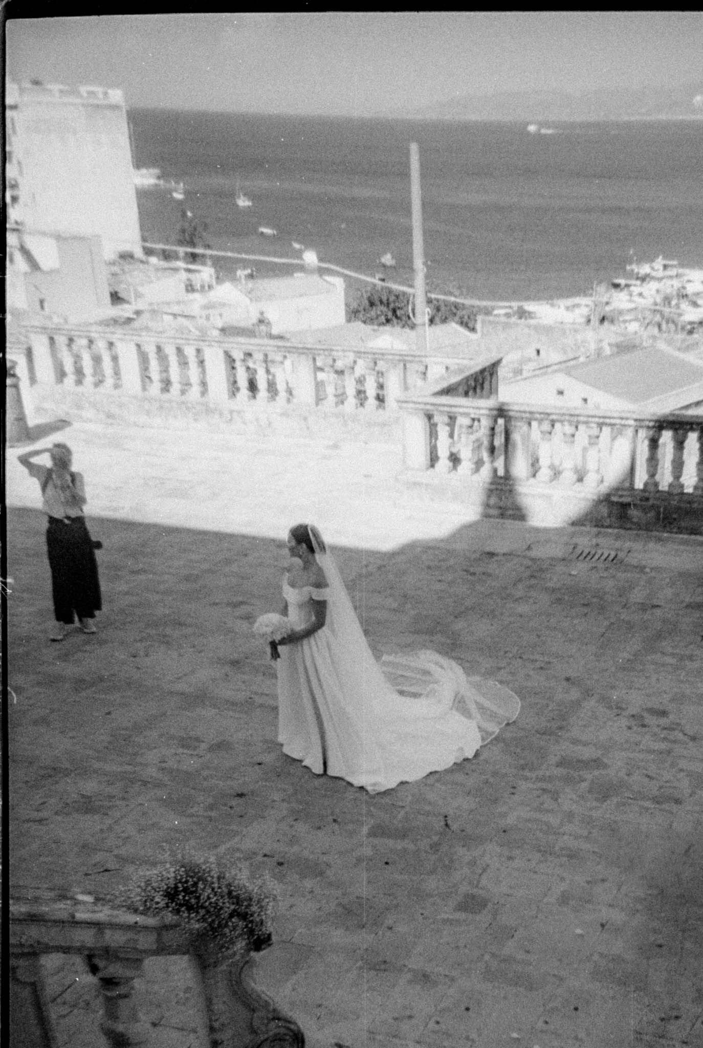 A black and white photograph of a seaside terrace with stone balustrades overlooking the ocean.
