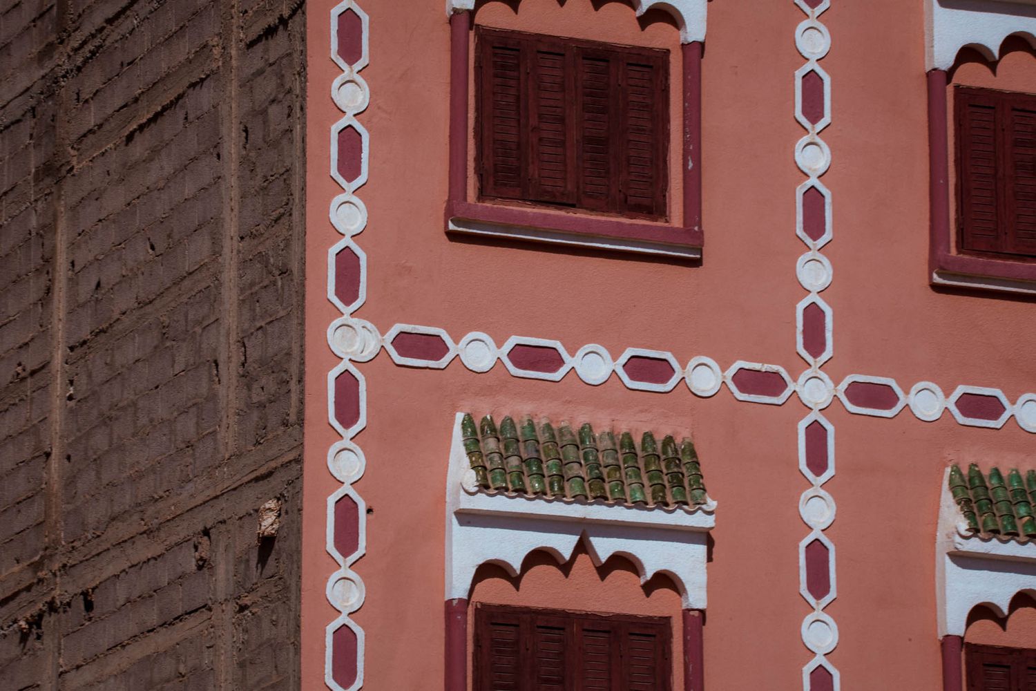 Ornate pink and white architectural details decorate the exterior walls and windows of a historic building.