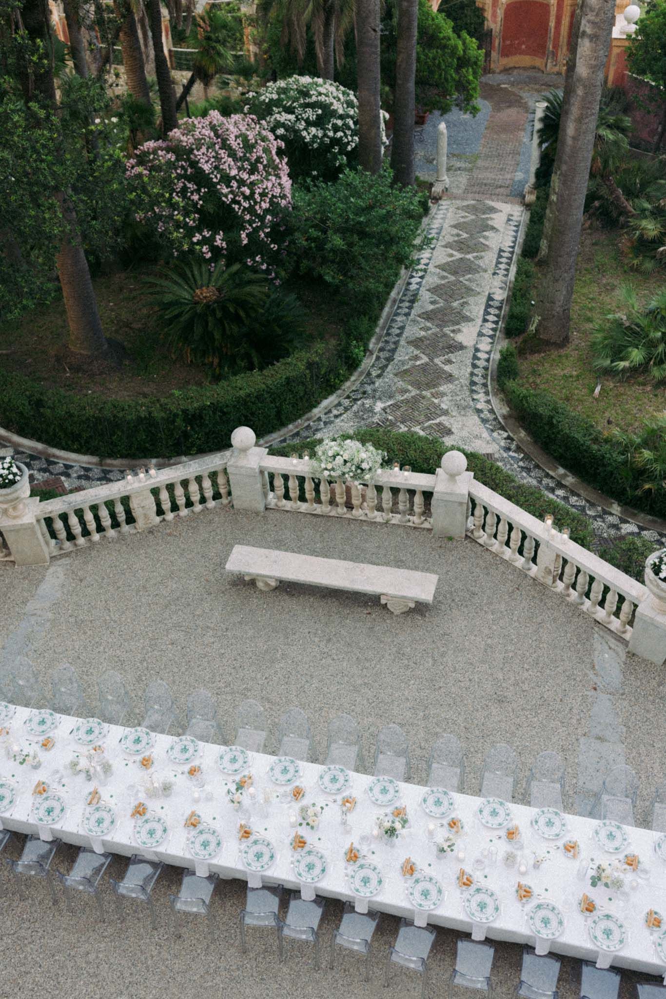 Curved stone staircase with ornate white balustrades and gravel path in a garden setting.
