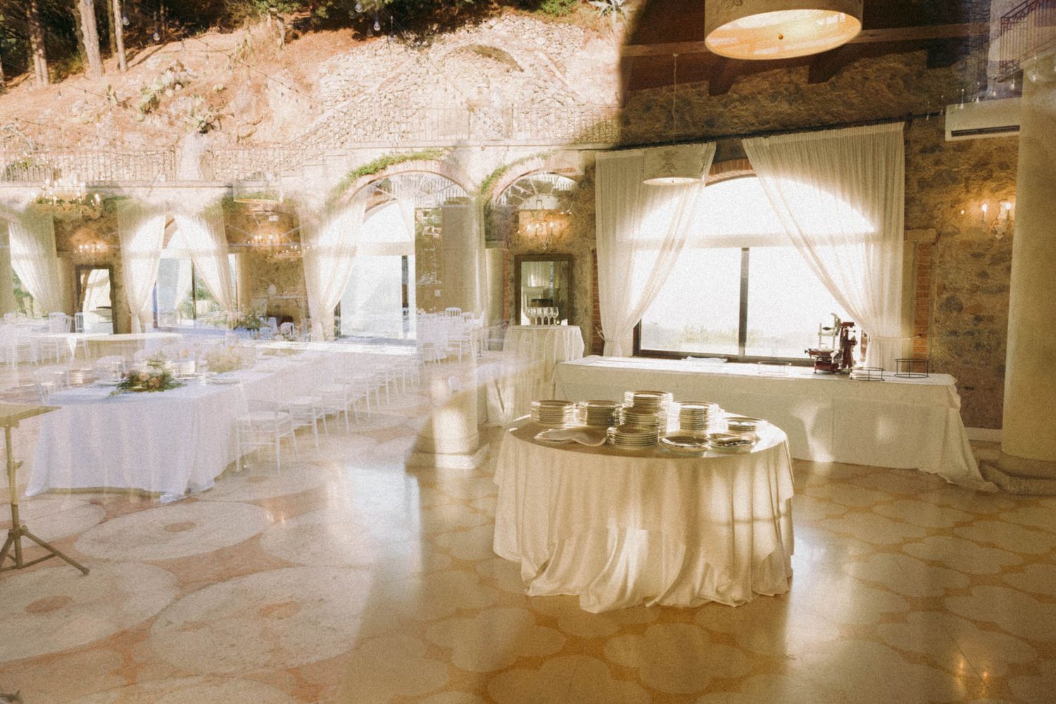 Elegant white wedding reception venue with stone walls and warm lighting creates a romantic atmosphere.