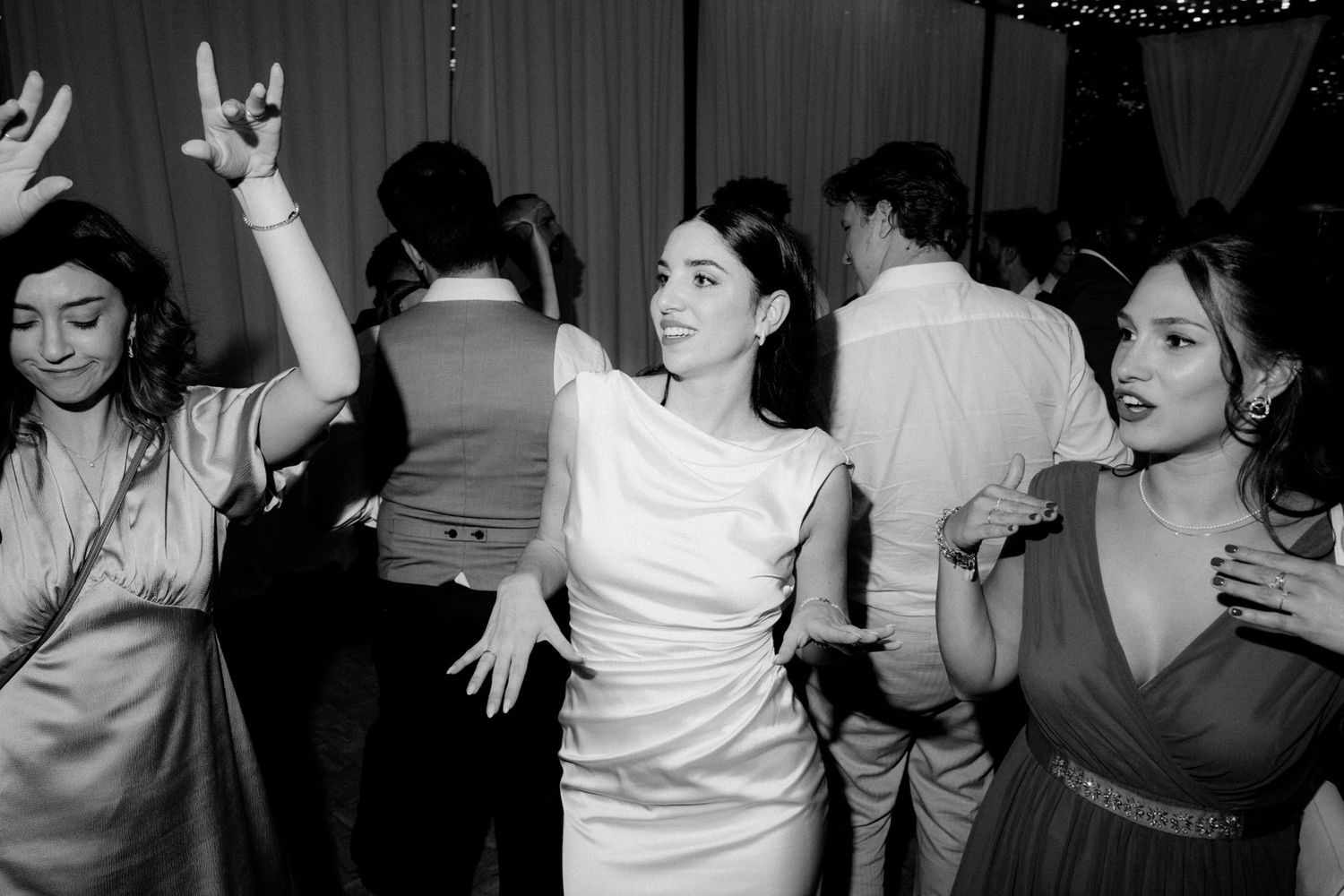Black and white photo showing people dancing and socializing at what appears to be a party or celebration.