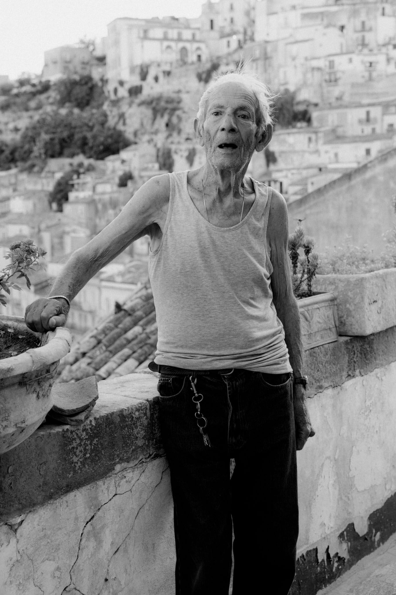 A series of black and white photos showing an elderly person gesturing expressively against a hillside backdrop.
