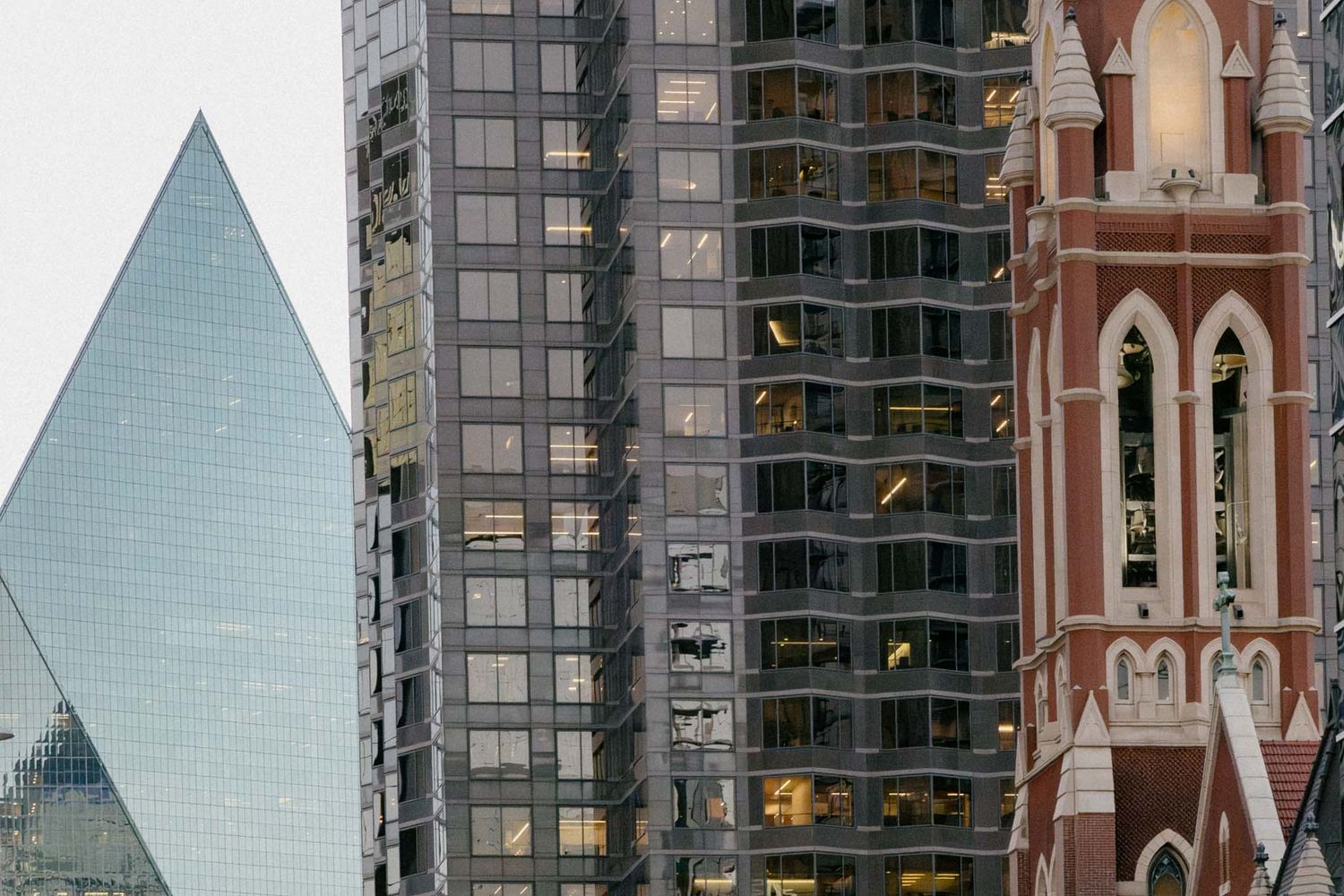 Modern glass skyscrapers and church steeples create a striking architectural contrast in an urban cityscape.