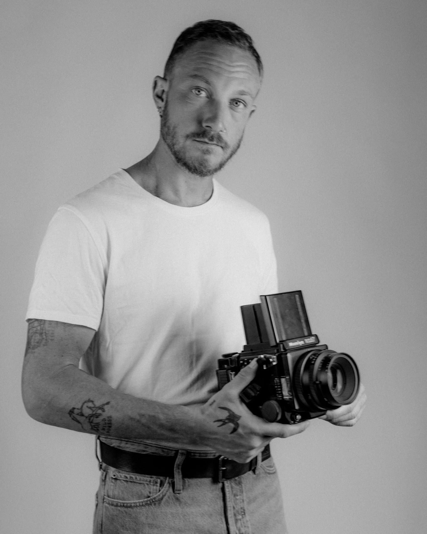 Black and white studio portraits of photographer demonstrating camera handling techniques.