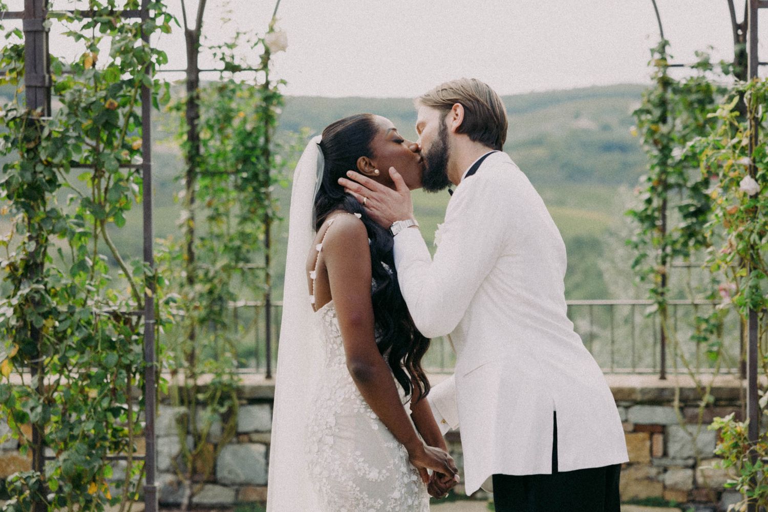A couple shares intimate moments during their outdoor wedding ceremony in a lush green garden setting.