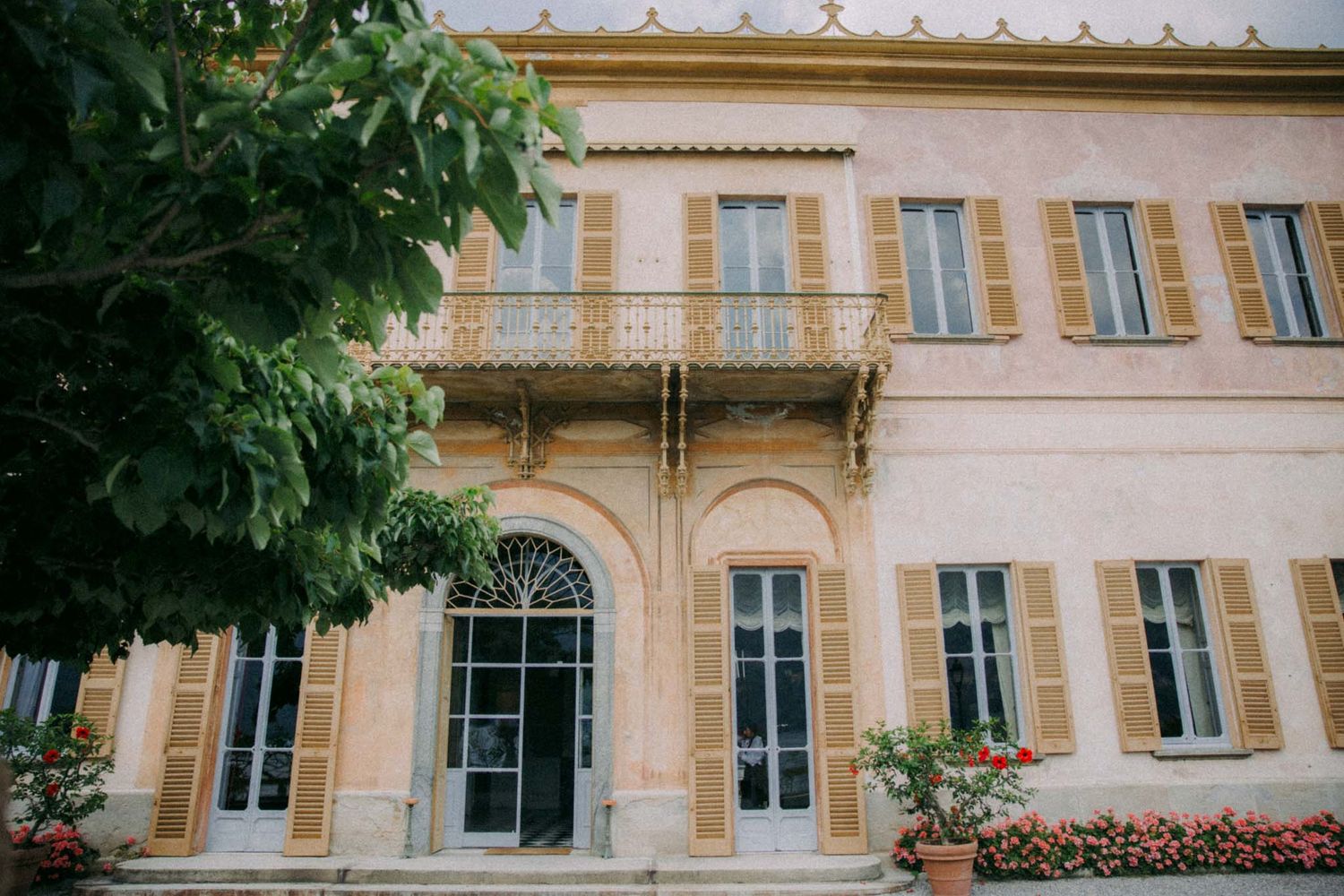 Exterior view of a classic French villa with beige stone walls, traditional shuttered windows and ornate architectural details.
