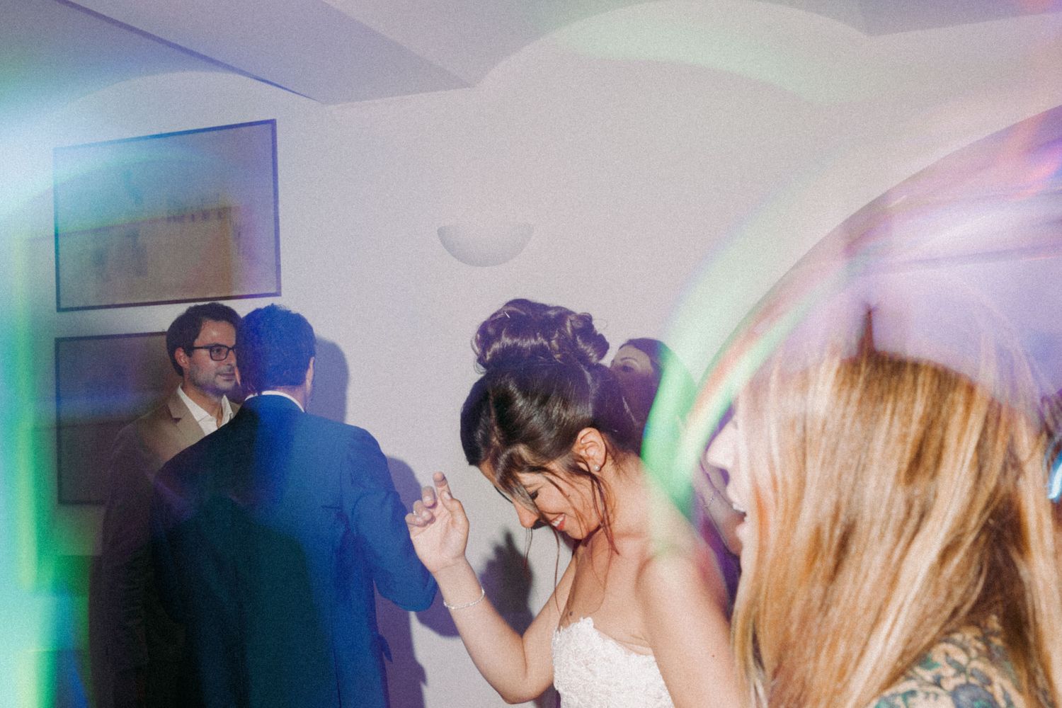People dancing at a wedding reception with colorful lighting and a blurred motion effect creating a dreamy atmosphere.