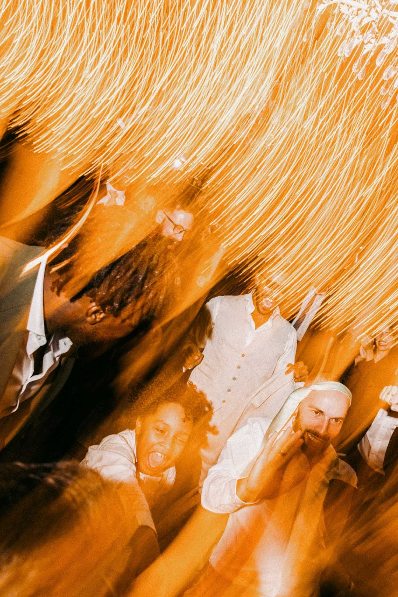 Abstract orange and white streaks create a dynamic pattern of light trails against a dark background.