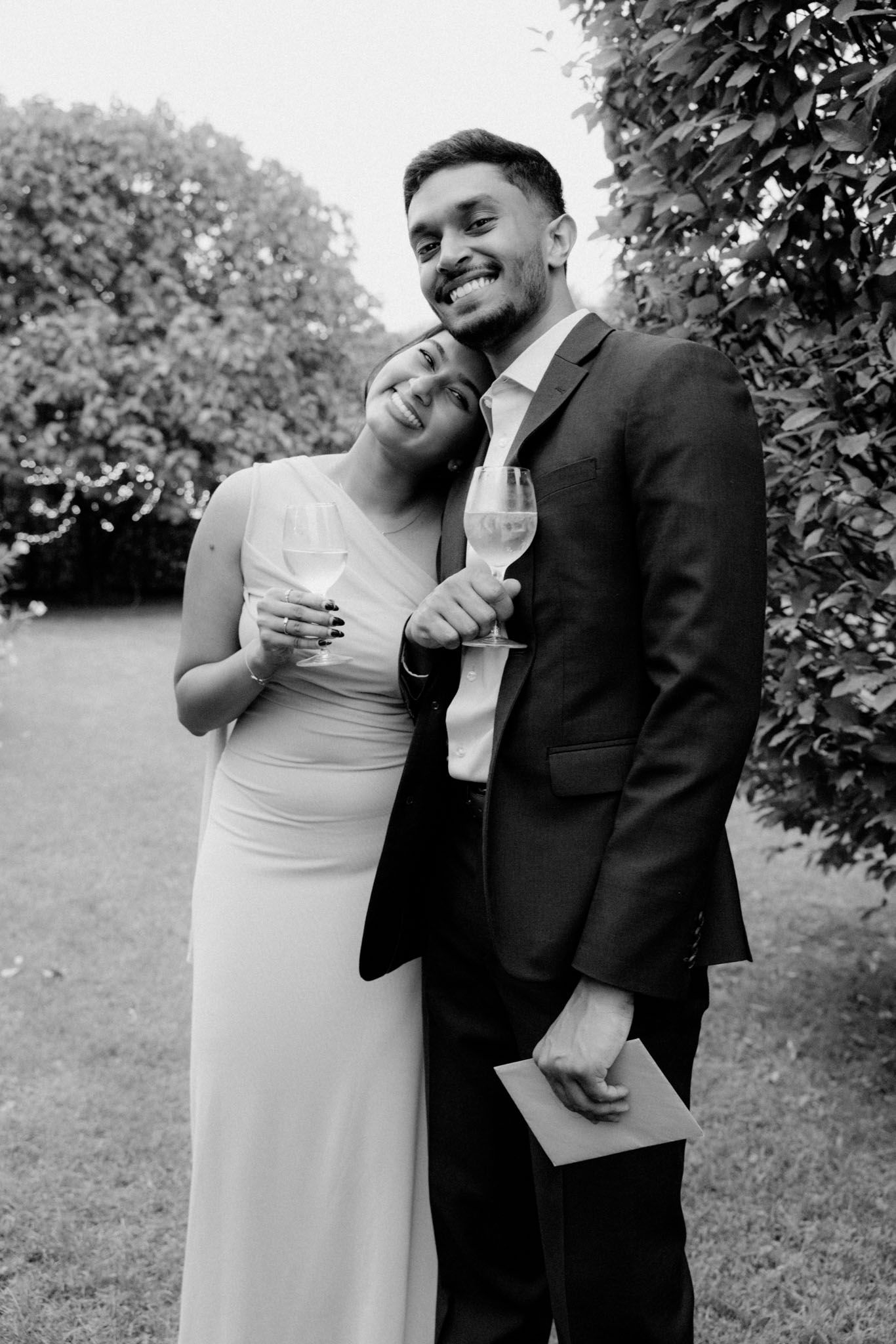Black and white photo series of a couple sharing joyful candid moments outdoors in formal attire.