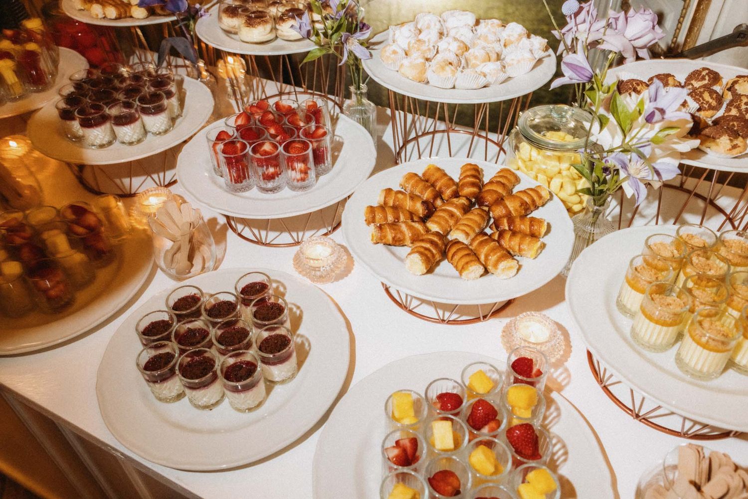 An elegant dessert table displays an assortment of bite-sized sweets, chocolates, and pastries on tiered platters.