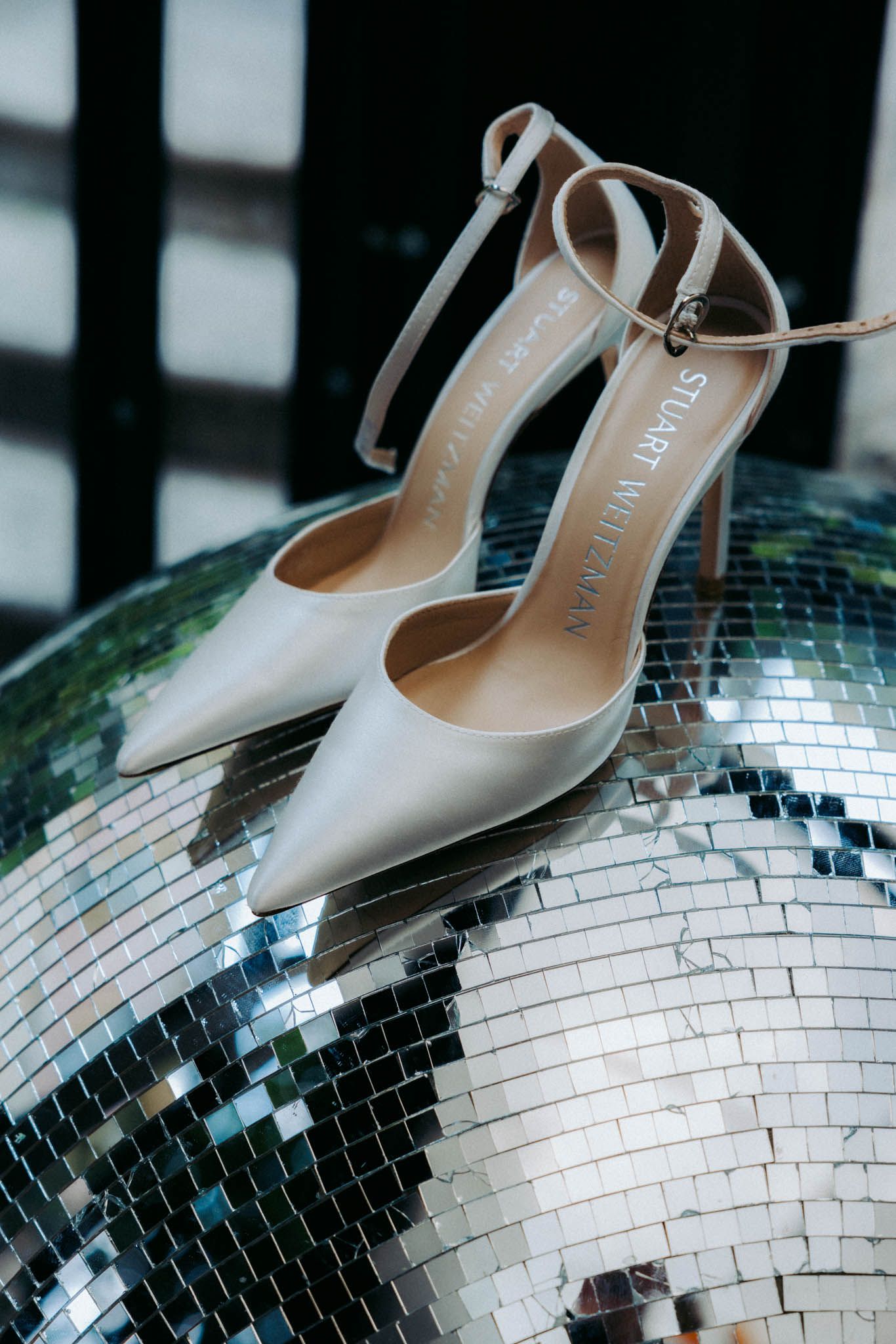 Silver high heel shoes elegantly displayed on a reflective disco ball surface in multiple angles.