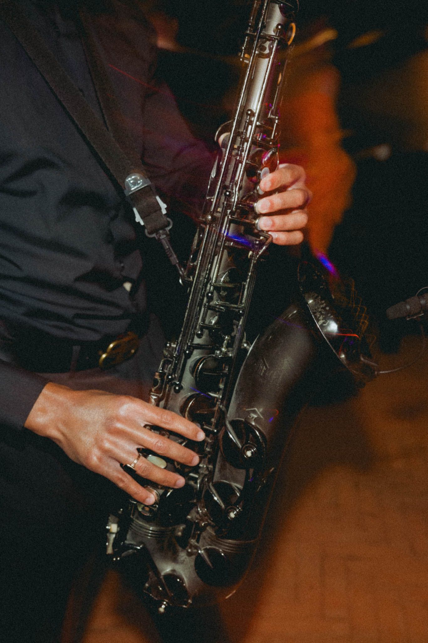 Close-up sequence of hands playing a saxophone against a dark background with warm lighting.