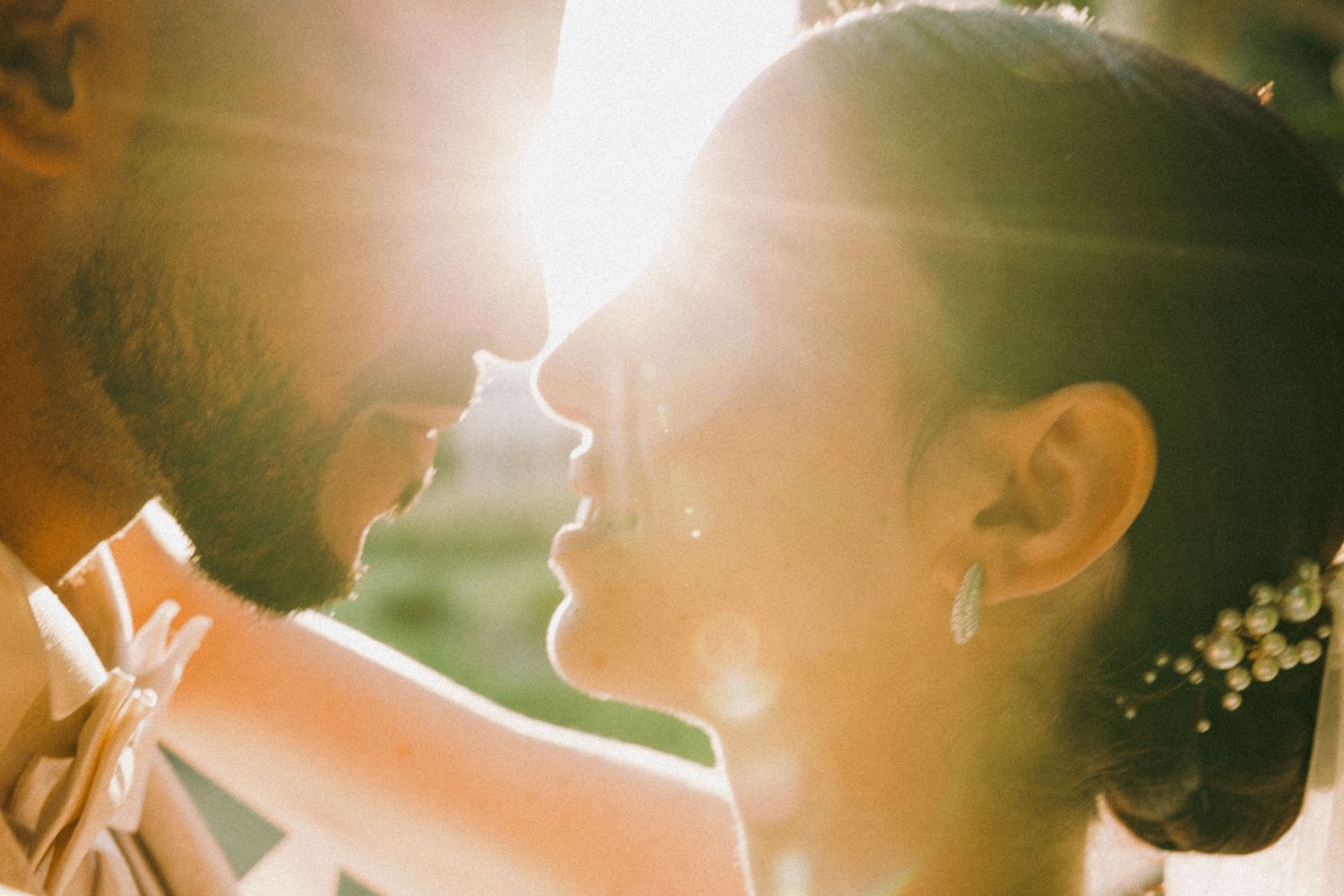 A romantic couple embraces in golden sunlight during their wedding celebration, creating a dreamy backlit silhouette.