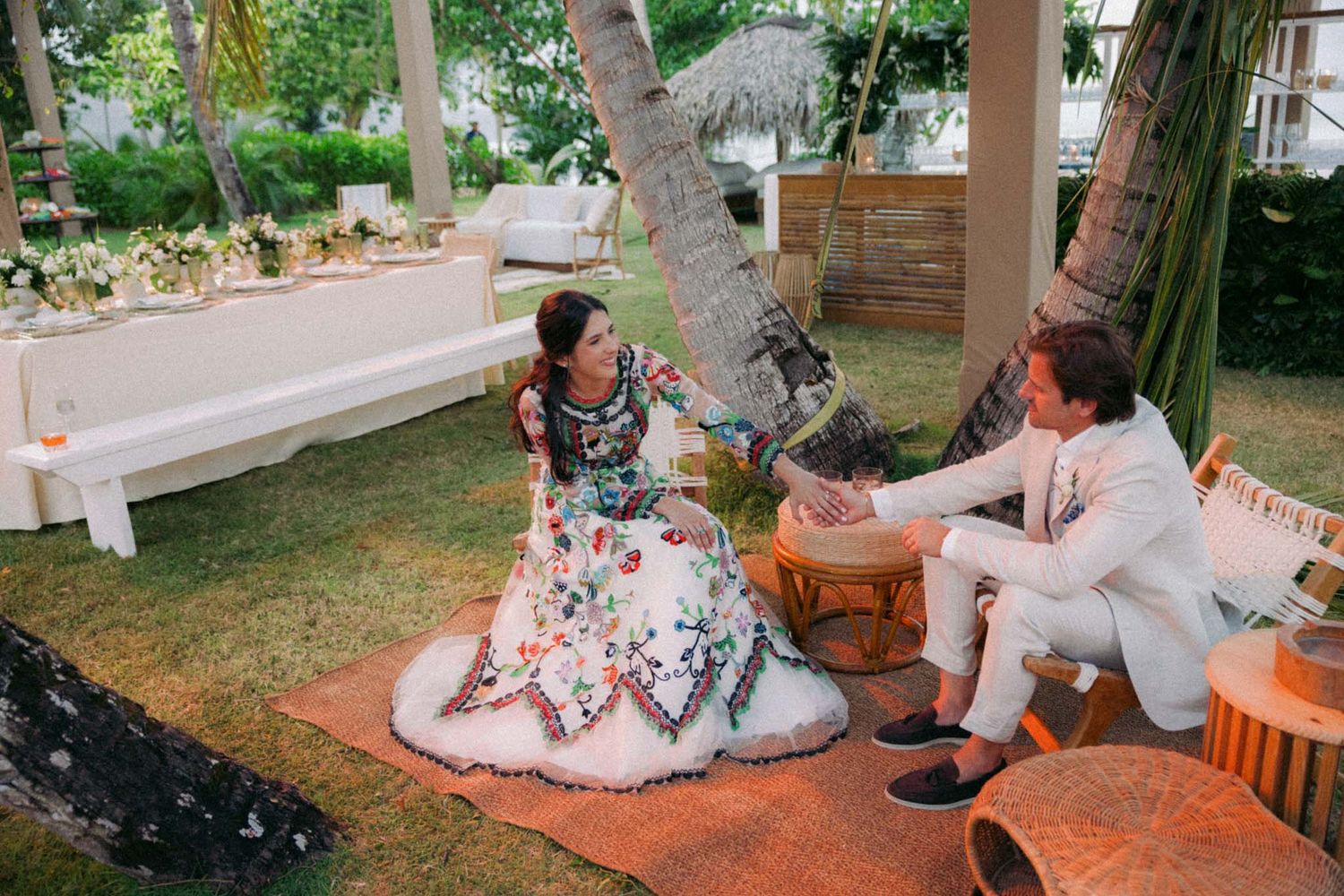 A group of people enjoying an outdoor garden party with orange and white decor on a sunny afternoon.