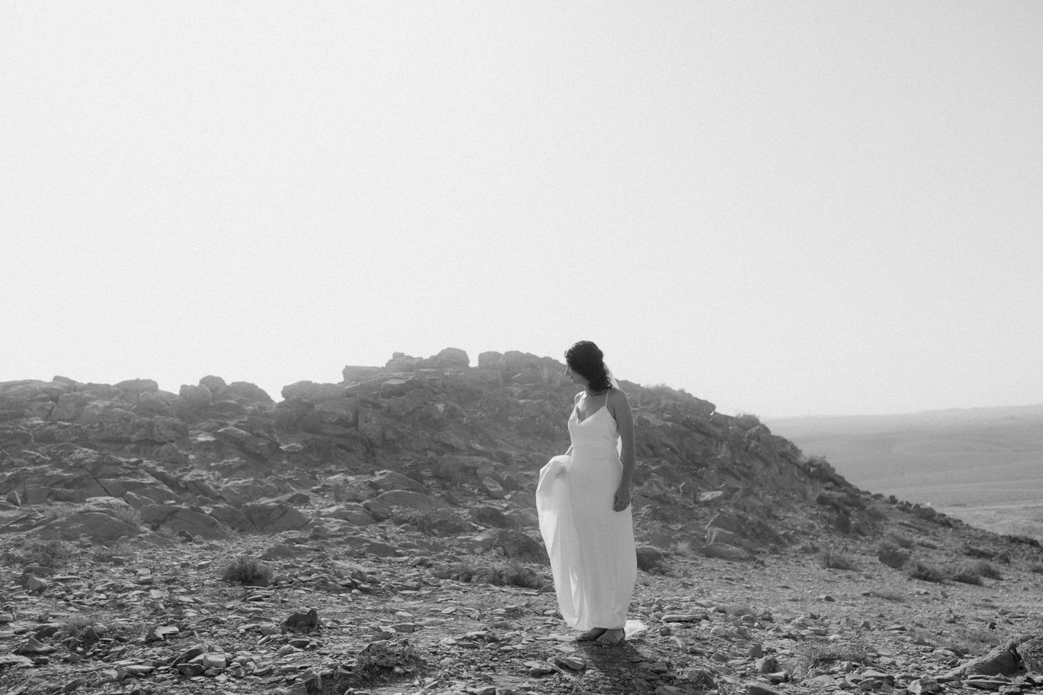 A series of black and white photographs showing a person in white walking along a rocky mountain ridge in misty conditions.