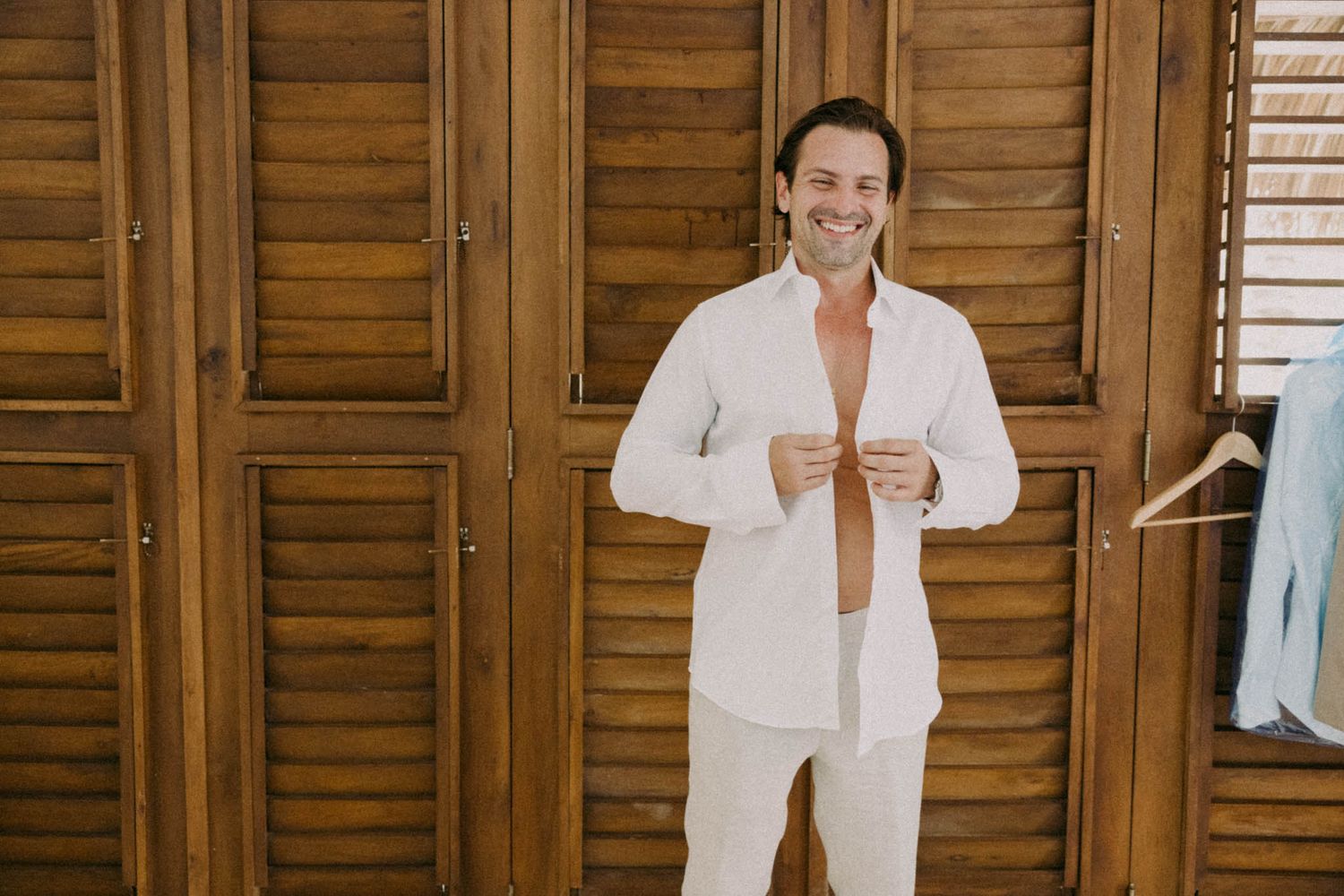 Person in white shirt poses against wooden shuttered wall in three different casual stances.
