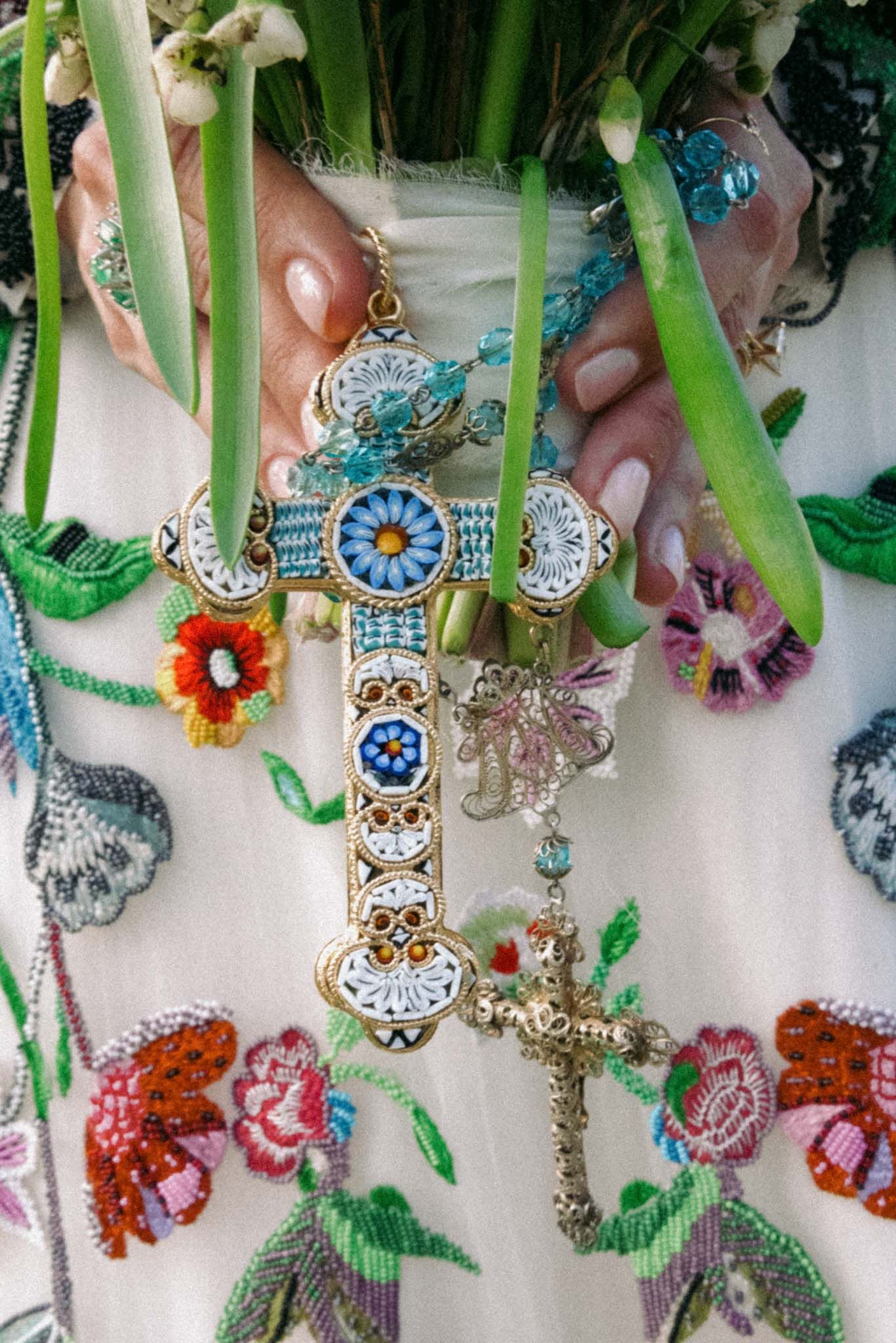 Colorful beaded jewelry and ornate accessories hanging on display with floral and skull motifs in turquoise and pink tones.